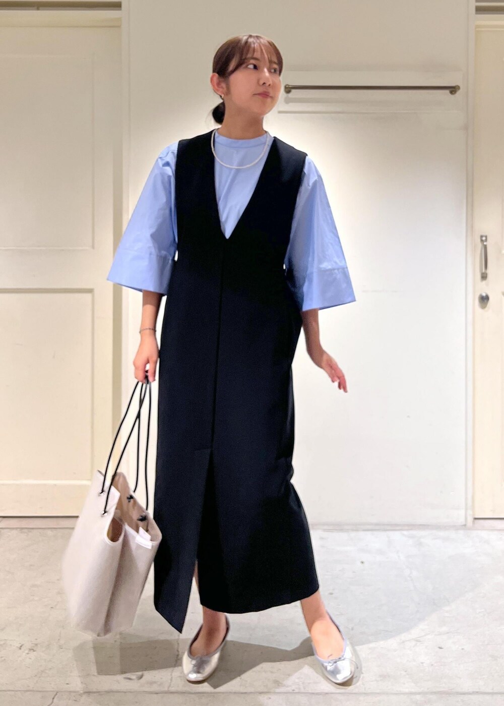 シルバー系のバレエシューズ、ブルー系のシャツ/ブラウス、ブラック系のジャンパースカートを着用したレディースの夏コーディネートの2枚目の写真
