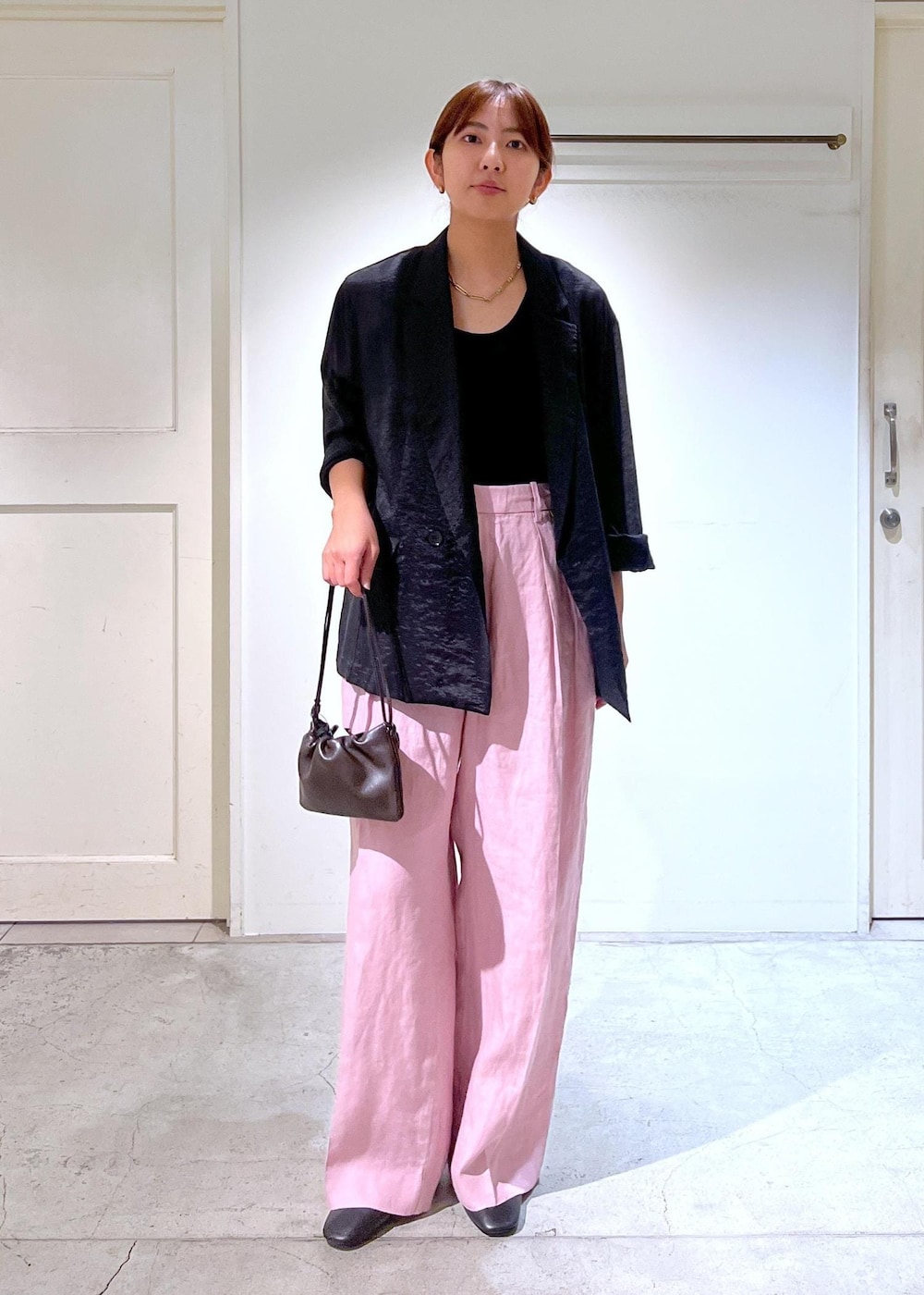 ピンク系のスラックス、ブラック系のタンクトップ、ブラック系のテーラードジャケットを着用したレディースの夏コーディネートの2枚目の写真