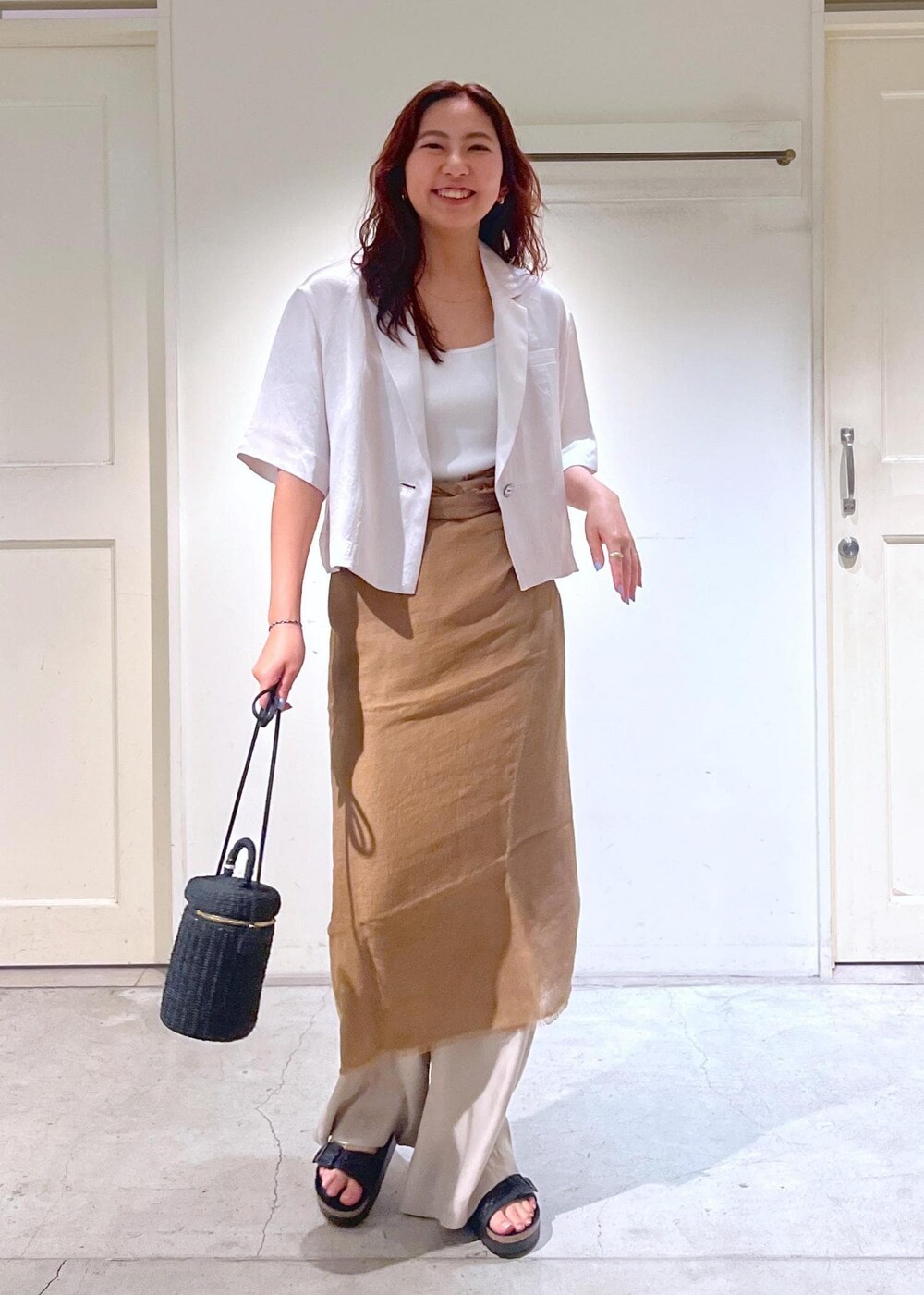 ブラック系のショルダーバッグ、ブラック系のサンダル、ホワイト系のタンクトップを着用したレディースの夏コーディネートの2枚目の写真