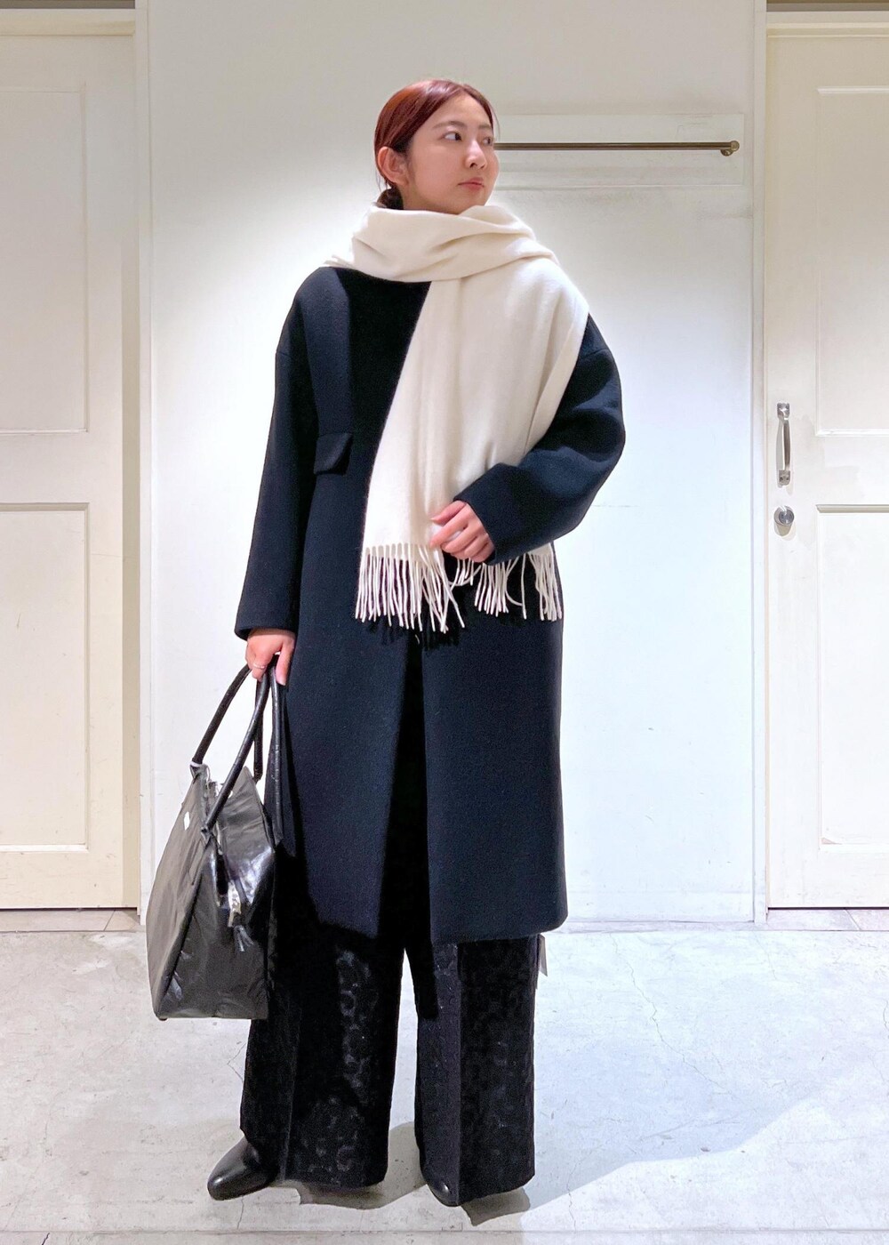 ブラック系のチェスターコート、ブラック系のブーツ、ブラック系のその他パンツを着用したレディースの冬コーディネートの3枚目の写真