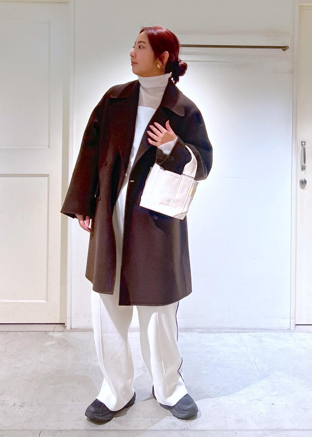 ブラウン系のピーコート、ホワイト系のニット/セーター、ホワイト系のキャミソールを着用したレディースの冬コーディネートの3枚目の写真