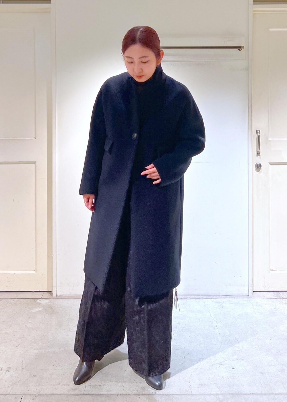 ブラック系のチェスターコート、ブラック系のブーツ、ブラック系のその他パンツを着用したレディースの冬コーディネートの4枚目の写真