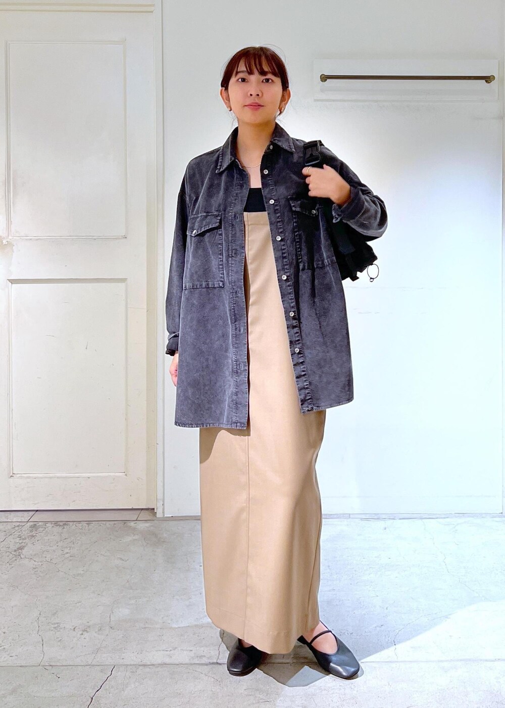 ブラック系のパンプス、グレー系のシャツ/ブラウス、ベージュ系のジャンパースカートを着用したレディースの秋コーディネートの2枚目の写真