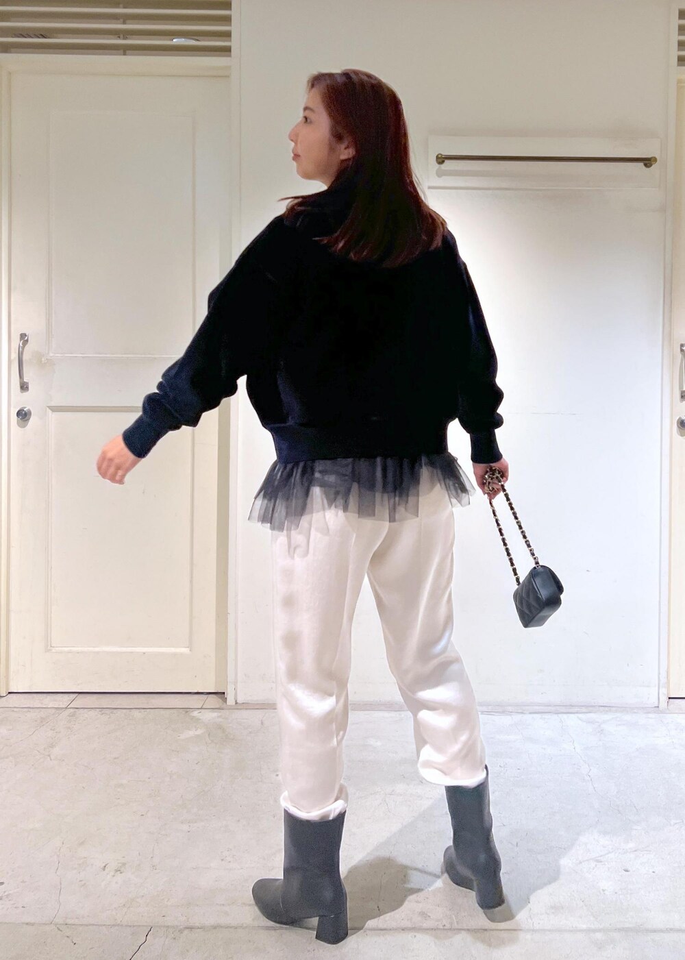 ブラック系のショルダーバッグ、ブラック系のニット/セーター、ブラック系のブーツを着用したレディースの秋コーディネートの4枚目の写真