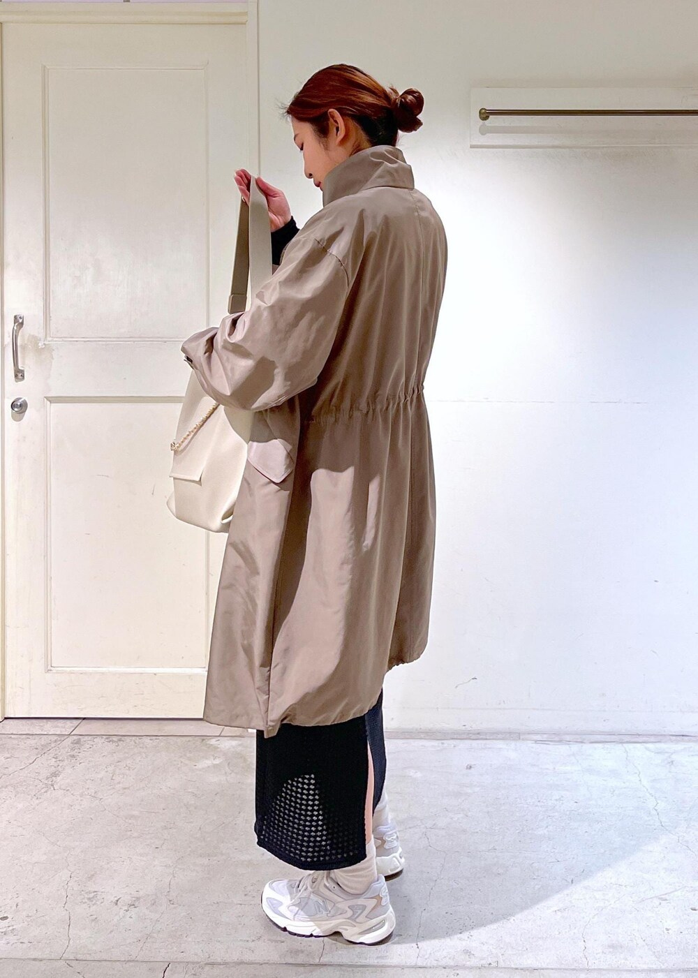 ホワイト系のスニーカー、ブラック系のスカート、ブラウン系のミリタリージャケットを着用したレディースの春コーディネートの4枚目の写真