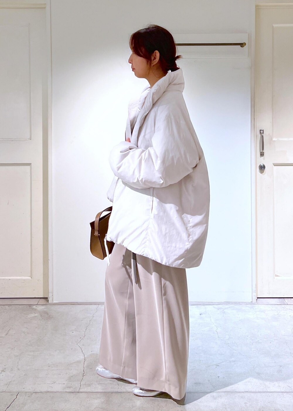 シルバー系のその他シューズ、ホワイト系のダウンジャケット/コート、ブラウン系のショルダーバッグを着用したレディースの秋コーディネートの6枚目の写真