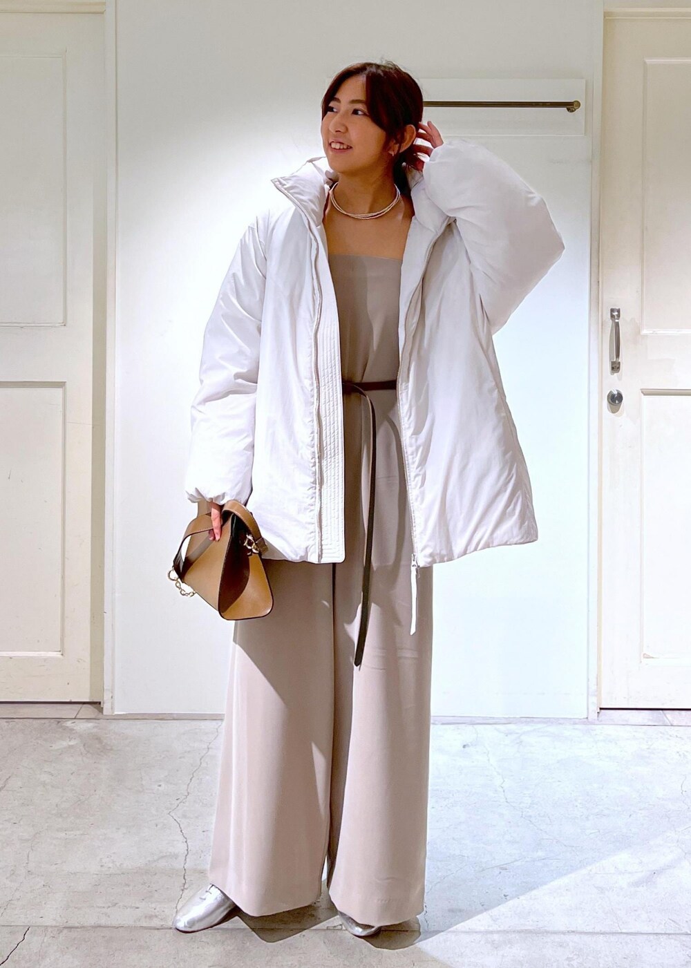 シルバー系のその他シューズ、ホワイト系のダウンジャケット/コート、ブラウン系のショルダーバッグを着用したレディースの秋コーディネートの2枚目の写真