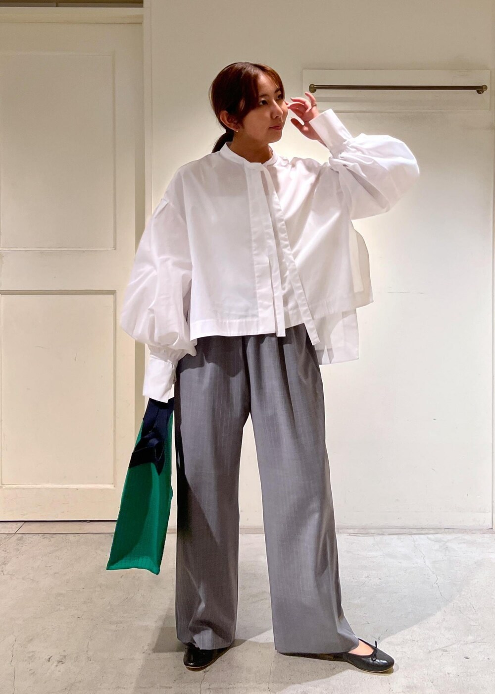 グレー系のスラックス、ホワイト系のシャツ/ブラウス、グリーン系のトートバッグを着用したレディースの夏コーディネートの2枚目の写真