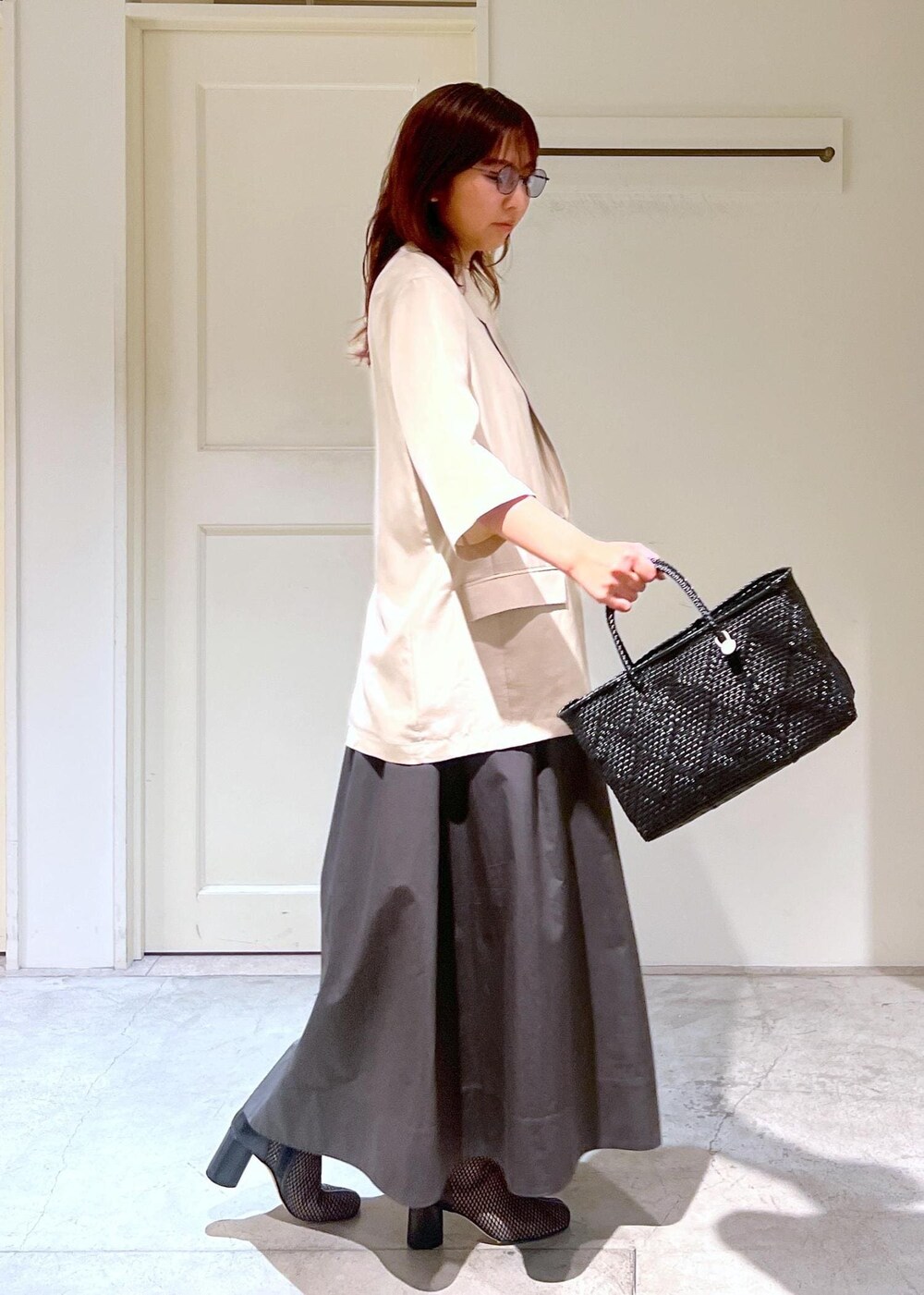 ブラック系のかごバッグ、ベージュ系のシャツ/ブラウス、グレー系のスカートを着用したレディースの春コーディネートの3枚目の写真