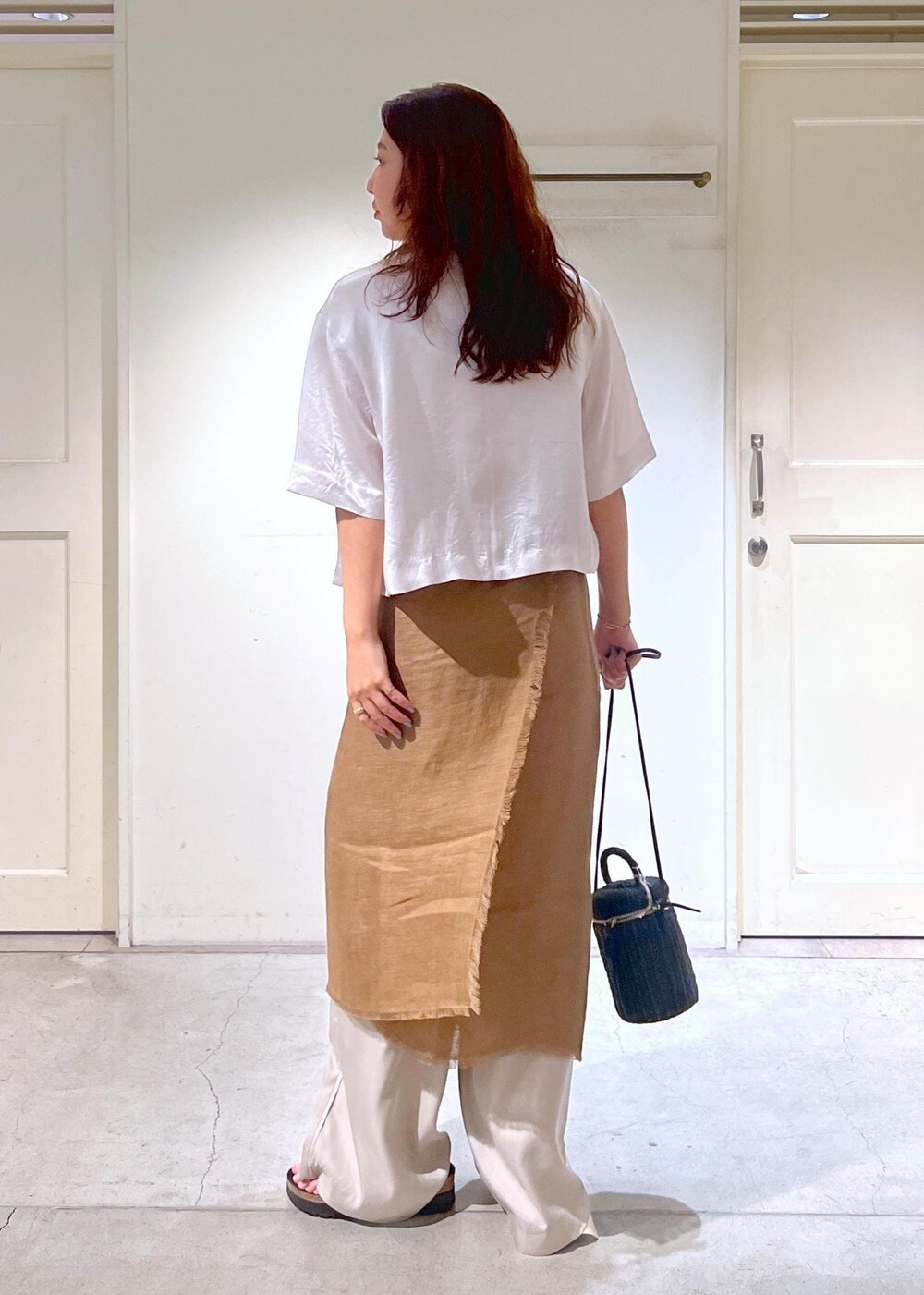 ブラック系のショルダーバッグ、ブラック系のサンダル、ホワイト系のタンクトップを着用したレディースの夏コーディネートの4枚目の写真