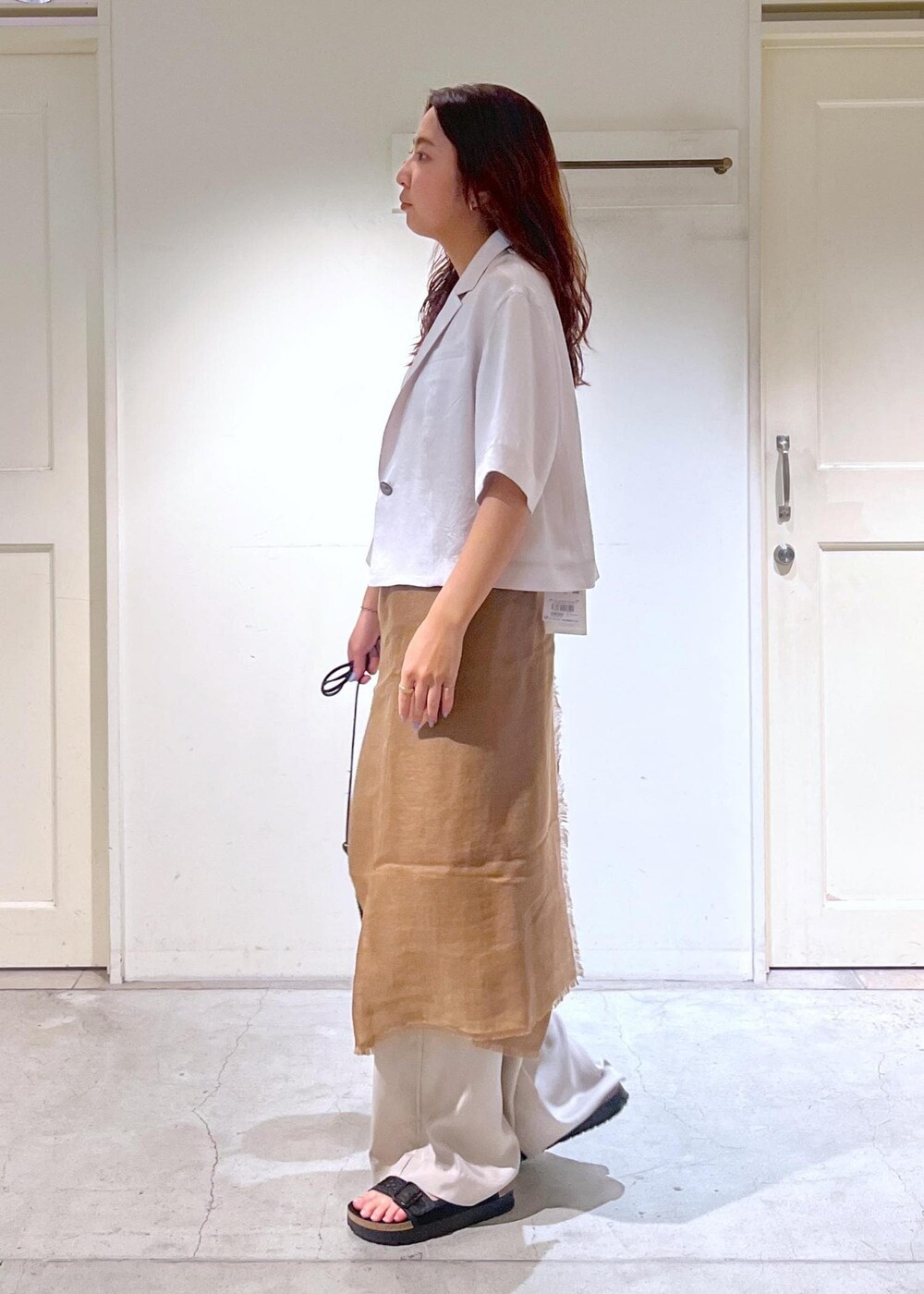 ブラック系のショルダーバッグ、ブラック系のサンダル、ホワイト系のタンクトップを着用したレディースの夏コーディネートの3枚目の写真