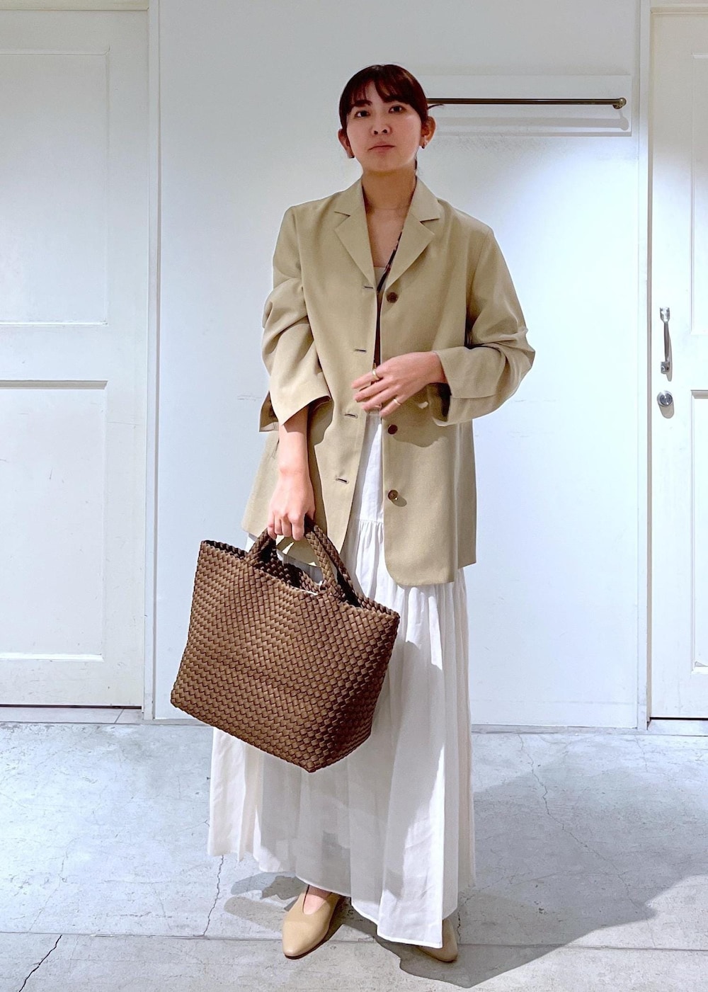 ベージュ系のパンプス、ベージュ系のテーラードジャケット、ホワイト系のスカートを着用したレディースの春コーディネートの2枚目の写真