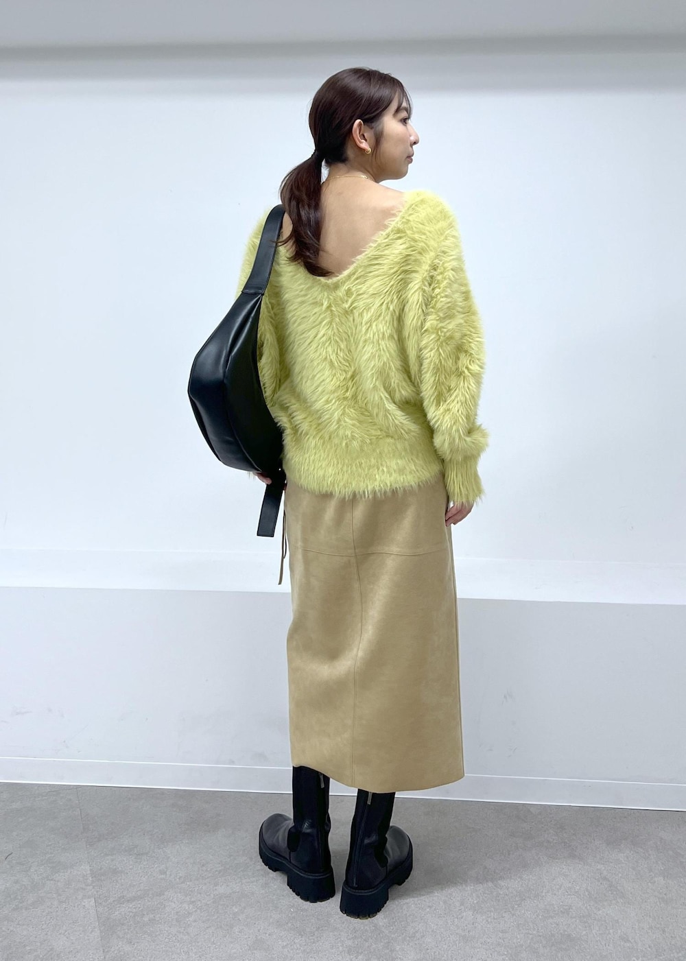 ブラック系のショルダーバッグ、ブラック系のブーツ、ベージュ系のスカートを着用したレディースの秋コーディネートの3枚目の写真