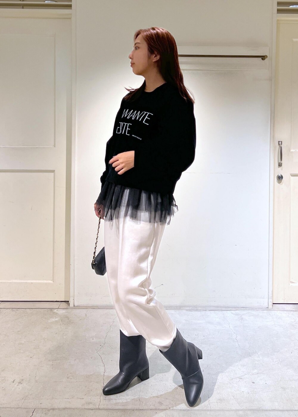 ブラック系のショルダーバッグ、ブラック系のニット/セーター、ブラック系のブーツを着用したレディースの秋コーディネートの2枚目の写真