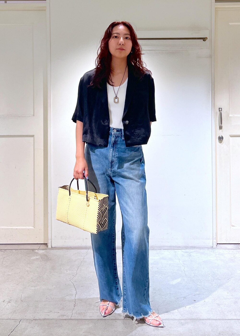 ブルー系のデニムパンツ、シルバー系のサンダル、ホワイト系のかごバッグを着用したレディースの夏コーディネートの2枚目の写真