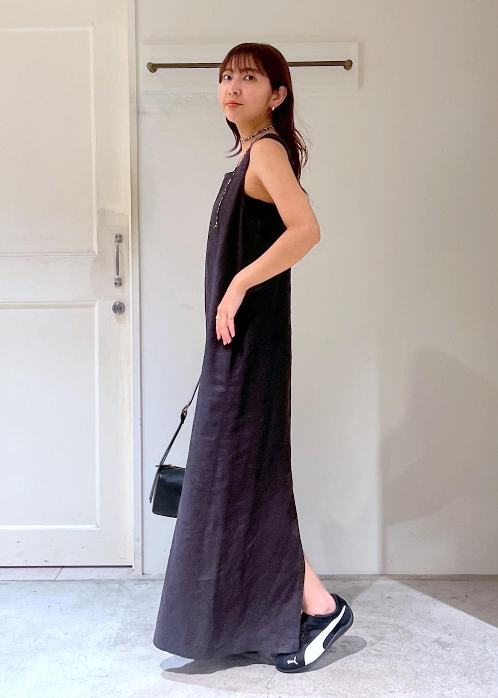 ブラック系のショルダーバッグ、ブラック系のジャンパースカート、ブラック系のスニーカーを着用したレディースの夏コーディネートの4枚目の写真