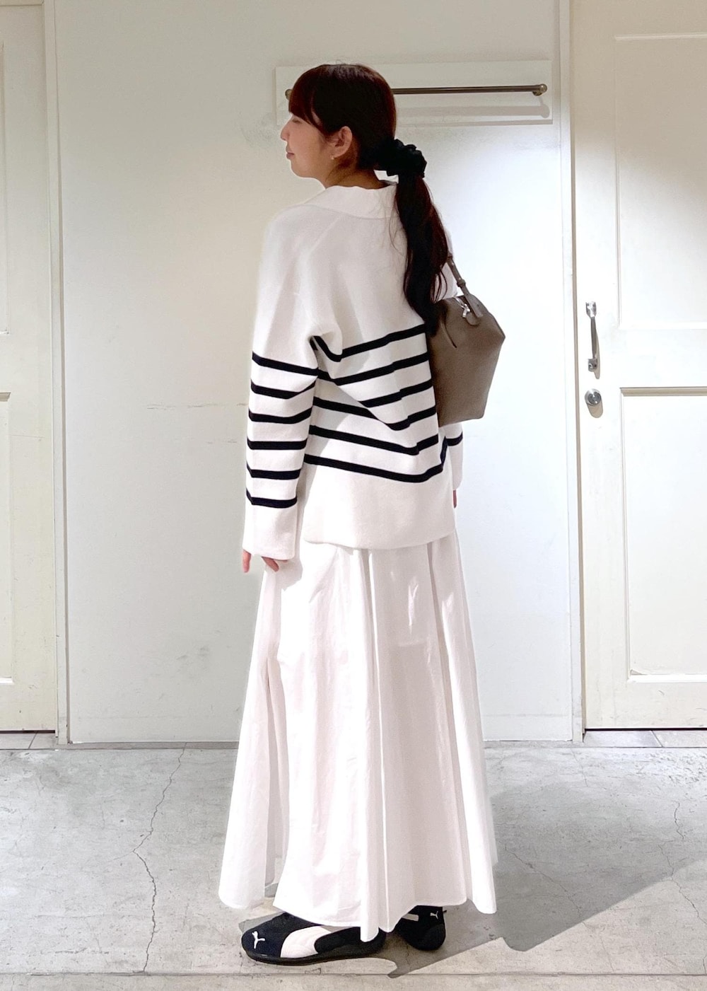 ホワイト系のニット/セーター、ホワイト系のスカート、ベージュ系のショルダーバッグを着用したレディースの春コーディネートの3枚目の写真