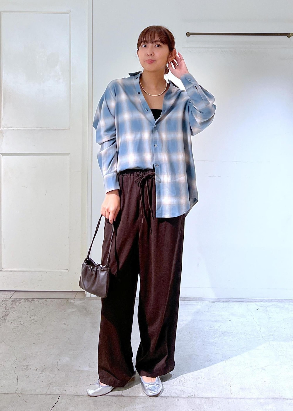 ブルー系のシャツ/ブラウス、ブラウン系のハンドバッグ、シルバー系のネックレスを着用したレディースの秋コーディネートの2枚目の写真