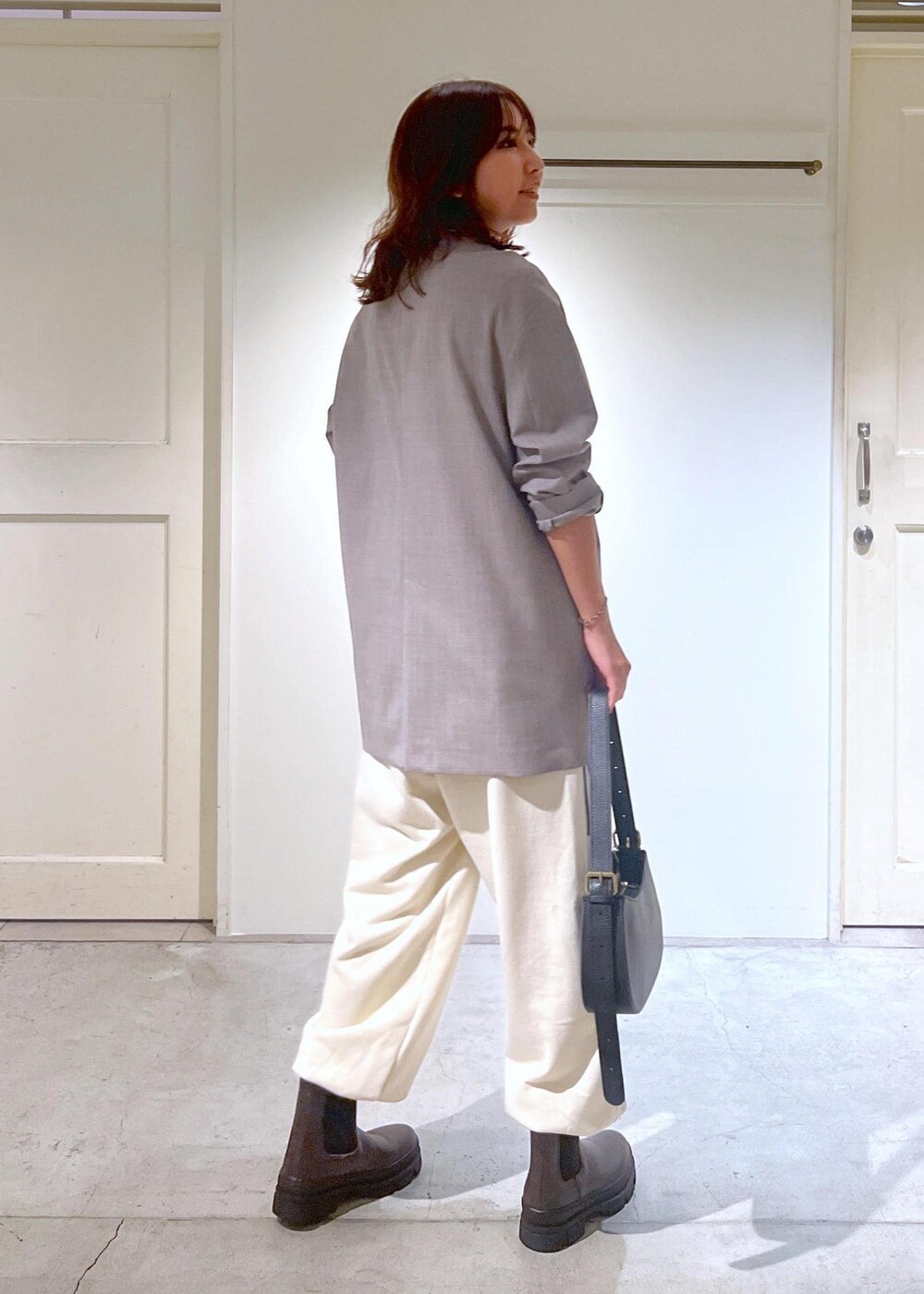 グレー系のノーカラージャケット、ホワイト系のスウェットパンツ、ブラック系のショルダーバッグを着用したレディースの秋コーディネートの3枚目の写真