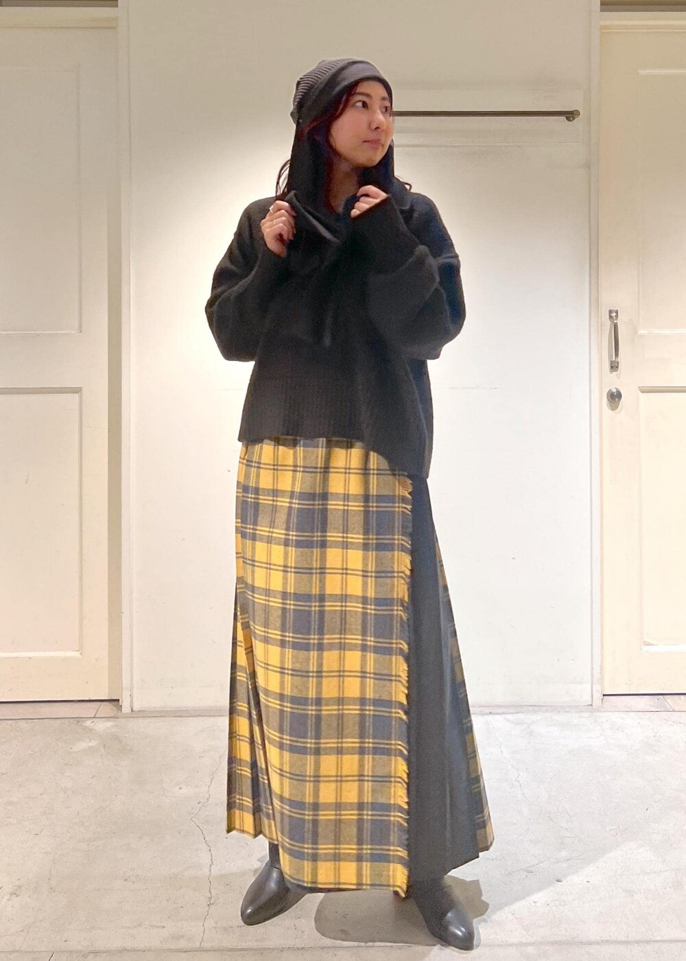 イエロー系のスカート、ブラック系のブーツ、ブラウン系のニット/セーターを着用したレディースの秋コーディネートの3枚目の写真