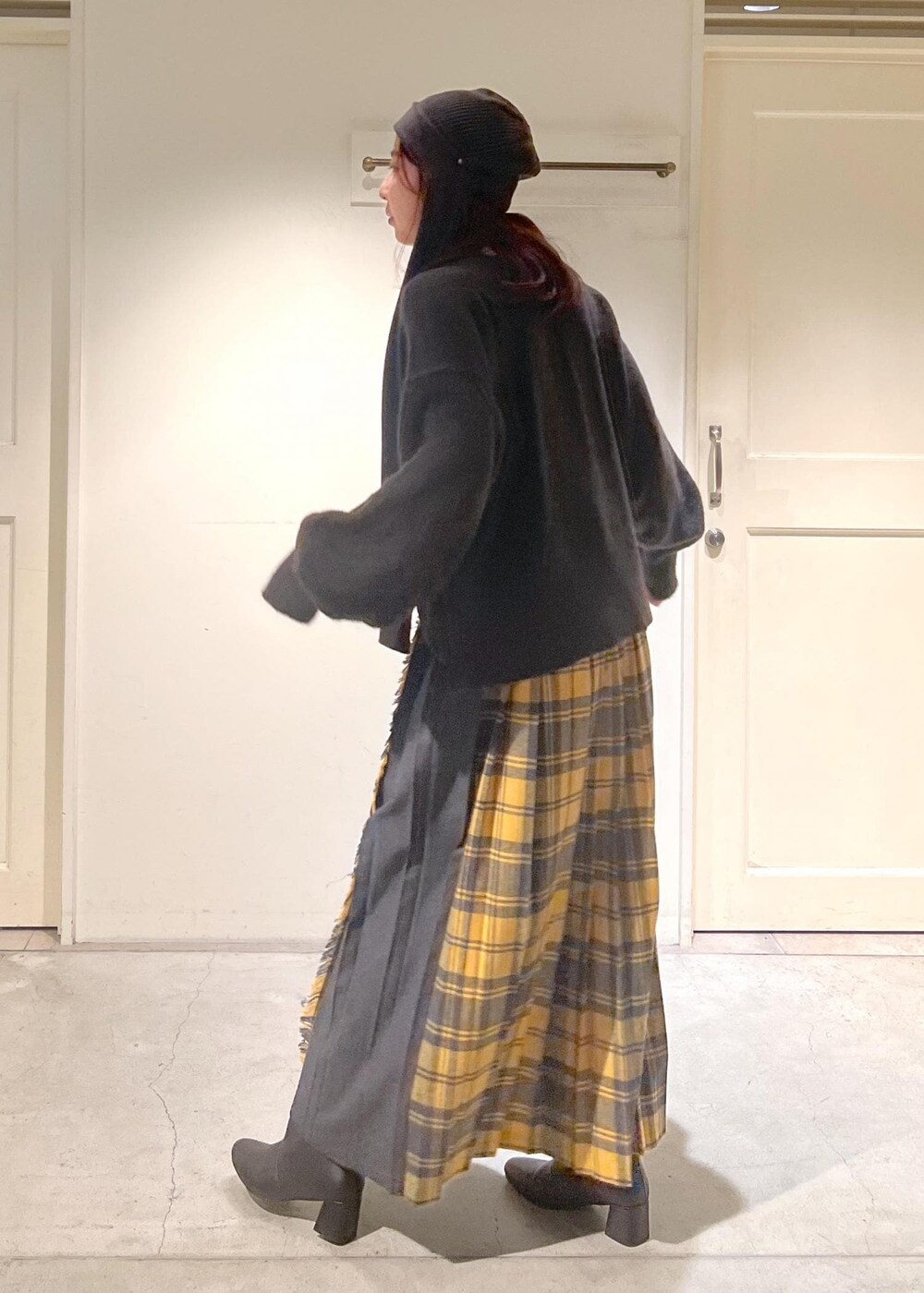 イエロー系のスカート、ブラック系のブーツ、ブラウン系のニット/セーターを着用したレディースの秋コーディネートの2枚目の写真