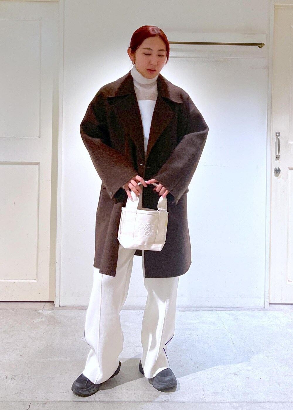 ブラウン系のピーコート、ホワイト系のニット/セーター、ホワイト系のキャミソールを着用したレディースの冬コーディネートの2枚目の写真