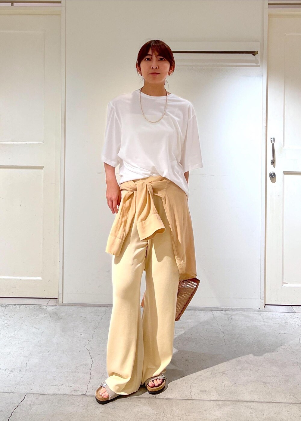 イエロー系のトートバッグ、ホワイト系のシャツ/ブラウス、ホワイト系のその他パンツを着用したレディースの夏コーディネートの2枚目の写真