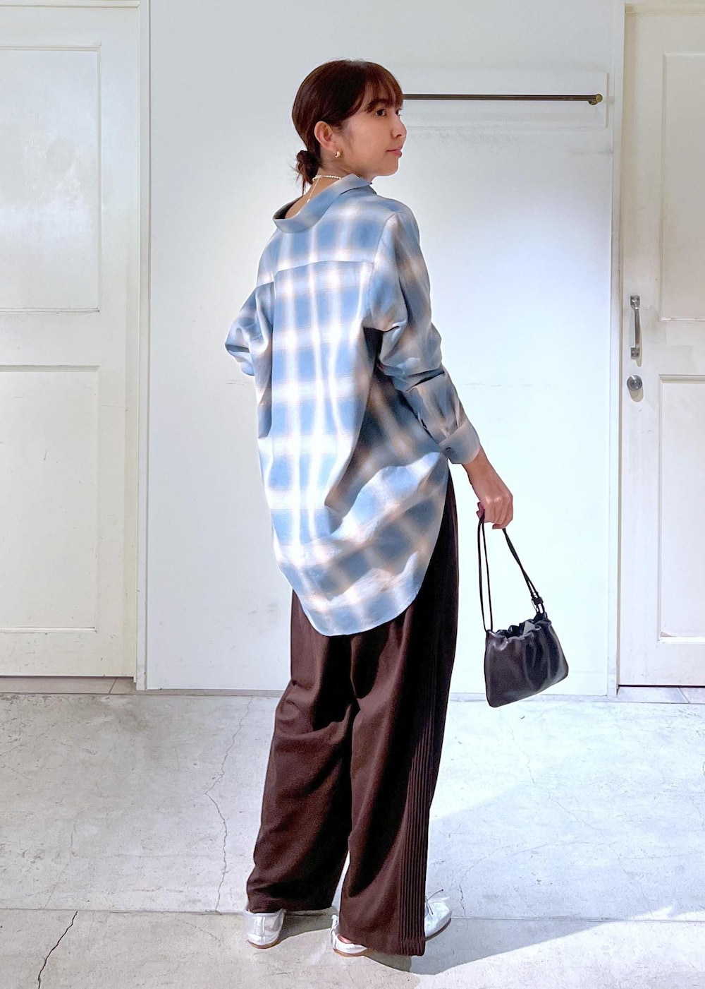 ブルー系のシャツ/ブラウス、ブラウン系のハンドバッグ、シルバー系のネックレスを着用したレディースの秋コーディネートの3枚目の写真