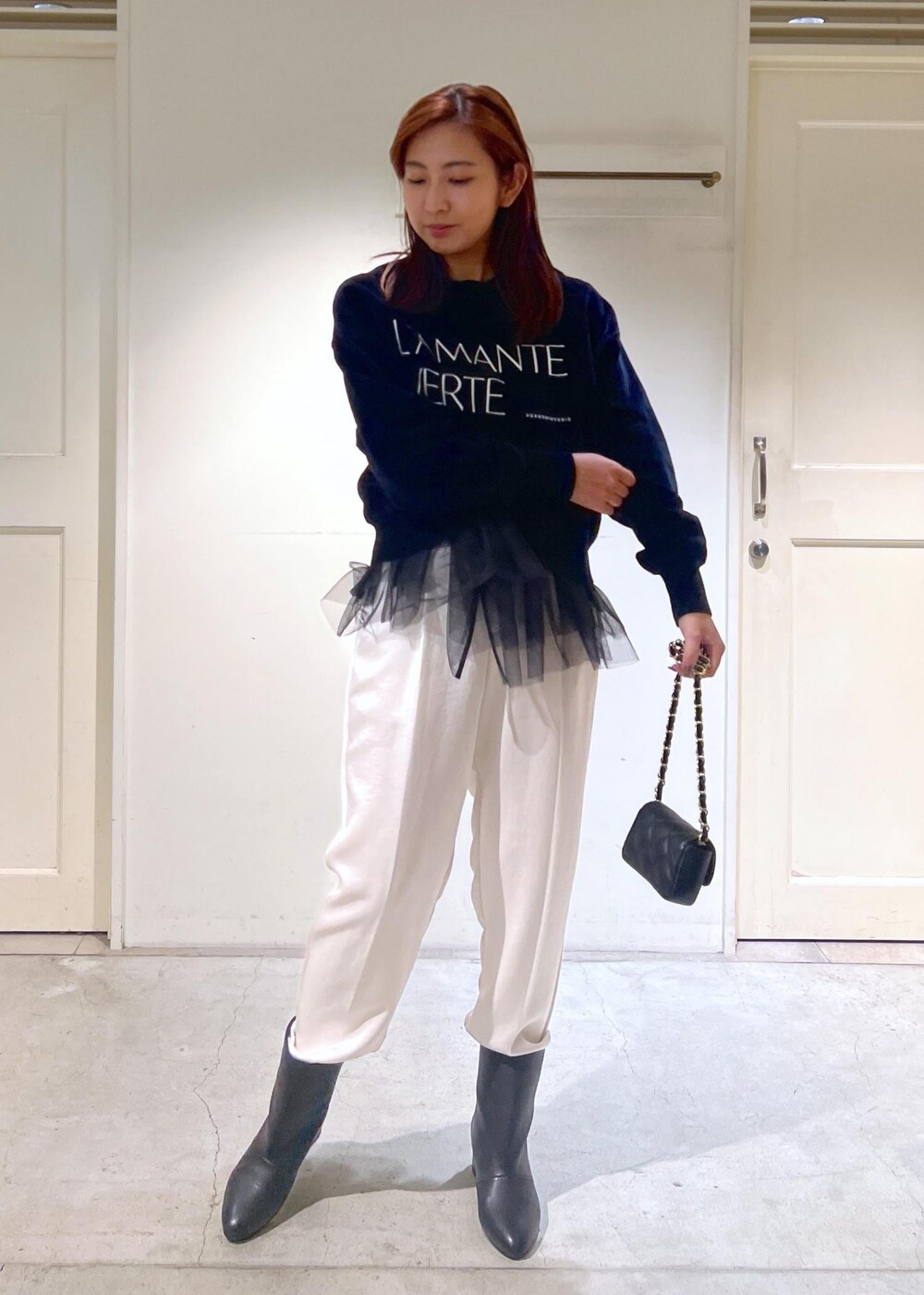 ブラック系のショルダーバッグ、ブラック系のニット/セーター、ブラック系のブーツを着用したレディースの秋コーディネートの3枚目の写真