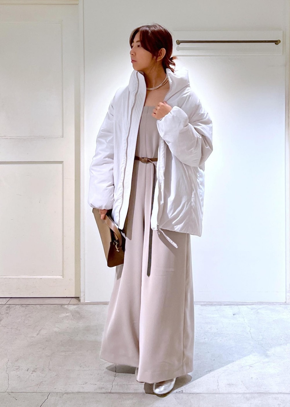 シルバー系のその他シューズ、ホワイト系のダウンジャケット/コート、ブラウン系のショルダーバッグを着用したレディースの秋コーディネートの3枚目の写真