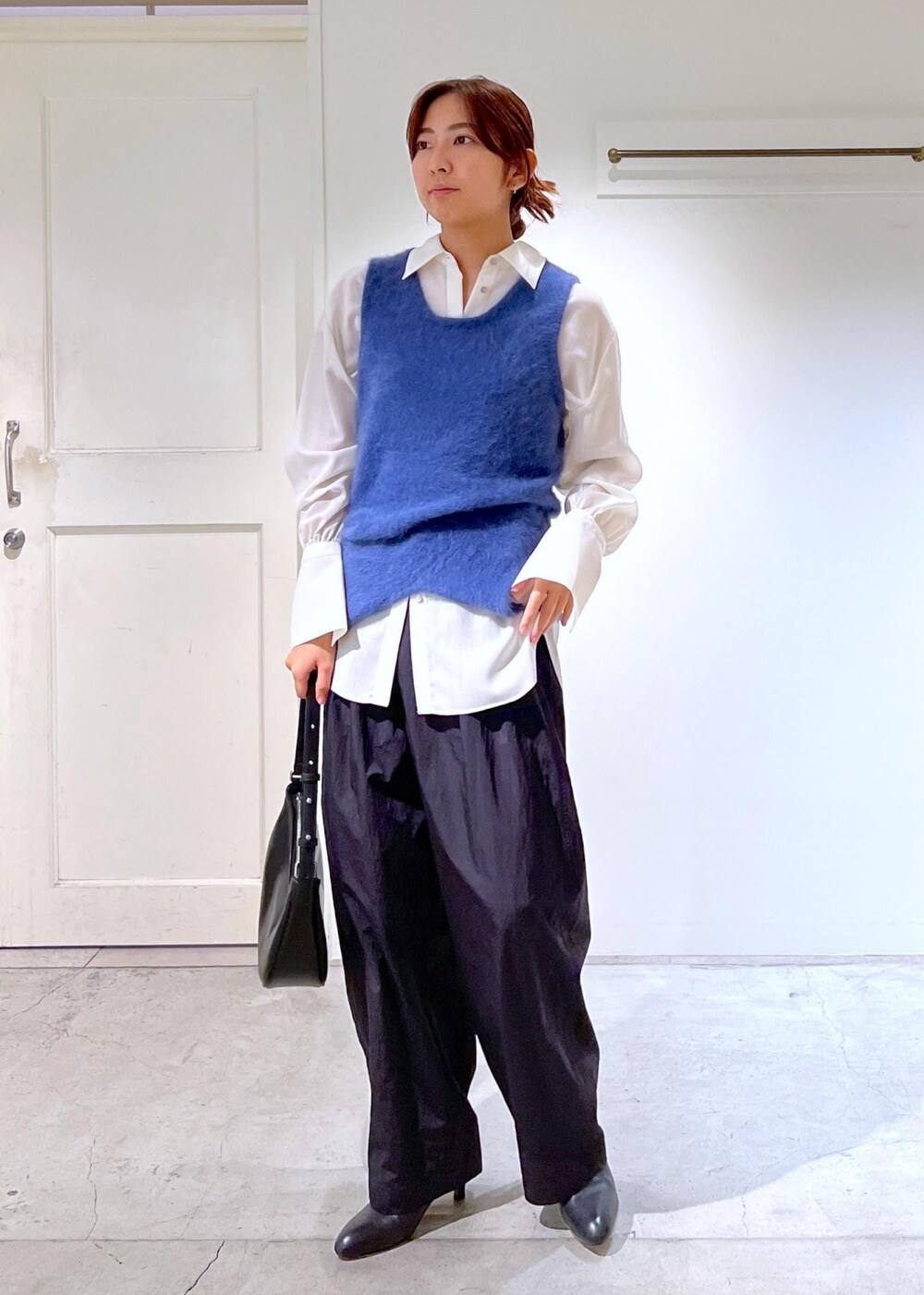 ブルー系のタンクトップ、ホワイト系のシャツ/ブラウス、ブラック系のブーツを着用したレディースの秋コーディネートの2枚目の写真