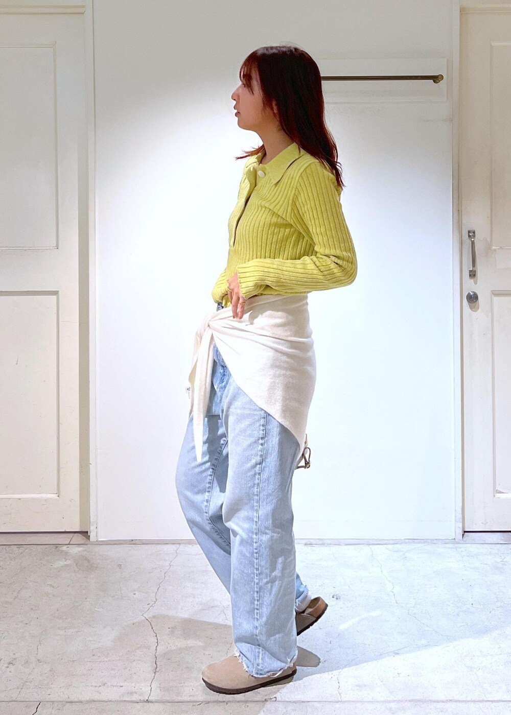 ベージュ系のボストンバッグ、イエロー系のニット/セーター、ブルー系のデニムパンツを着用したレディースの冬コーディネートの4枚目の写真