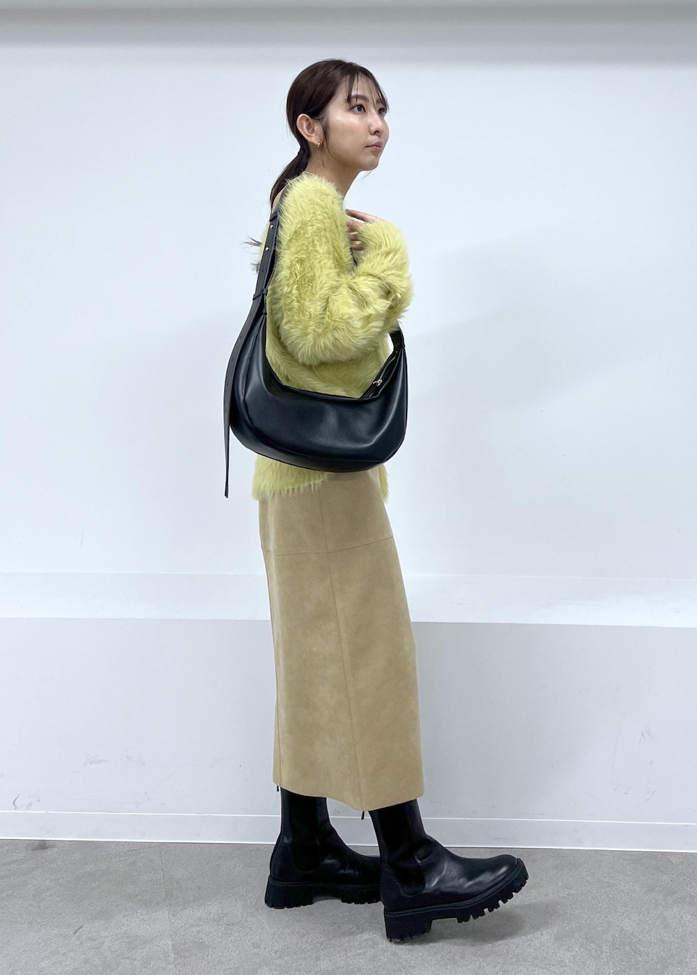 ブラック系のショルダーバッグ、ブラック系のブーツ、ベージュ系のスカートを着用したレディースの秋コーディネートの2枚目の写真