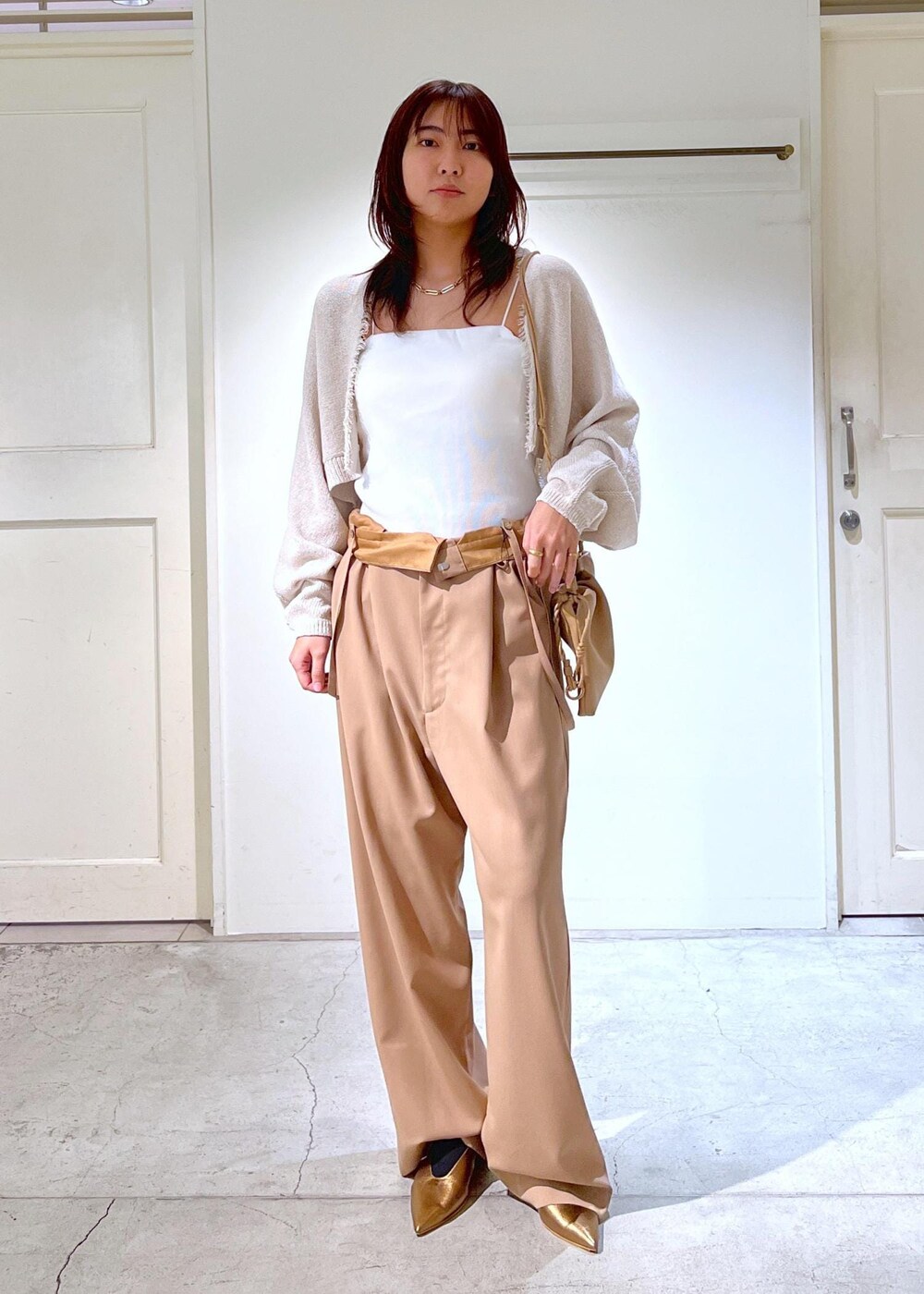 ホワイト系のチューブトップ、イエロー系のスラックス、ホワイト系のカーディガン/ボレロを着用したレディースの春コーディネートの3枚目の写真