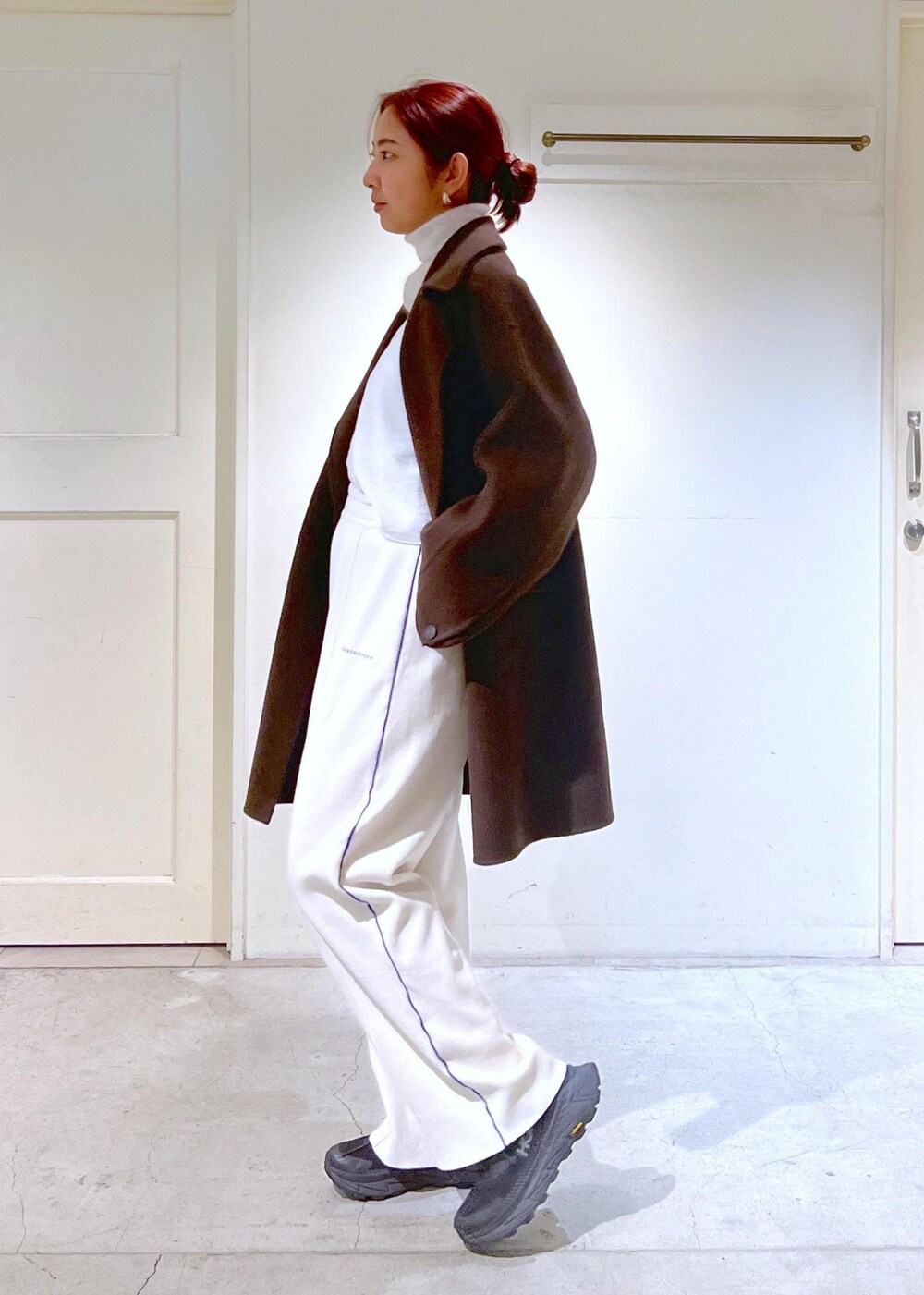 ブラウン系のピーコート、ホワイト系のニット/セーター、ホワイト系のキャミソールを着用したレディースの冬コーディネートの4枚目の写真