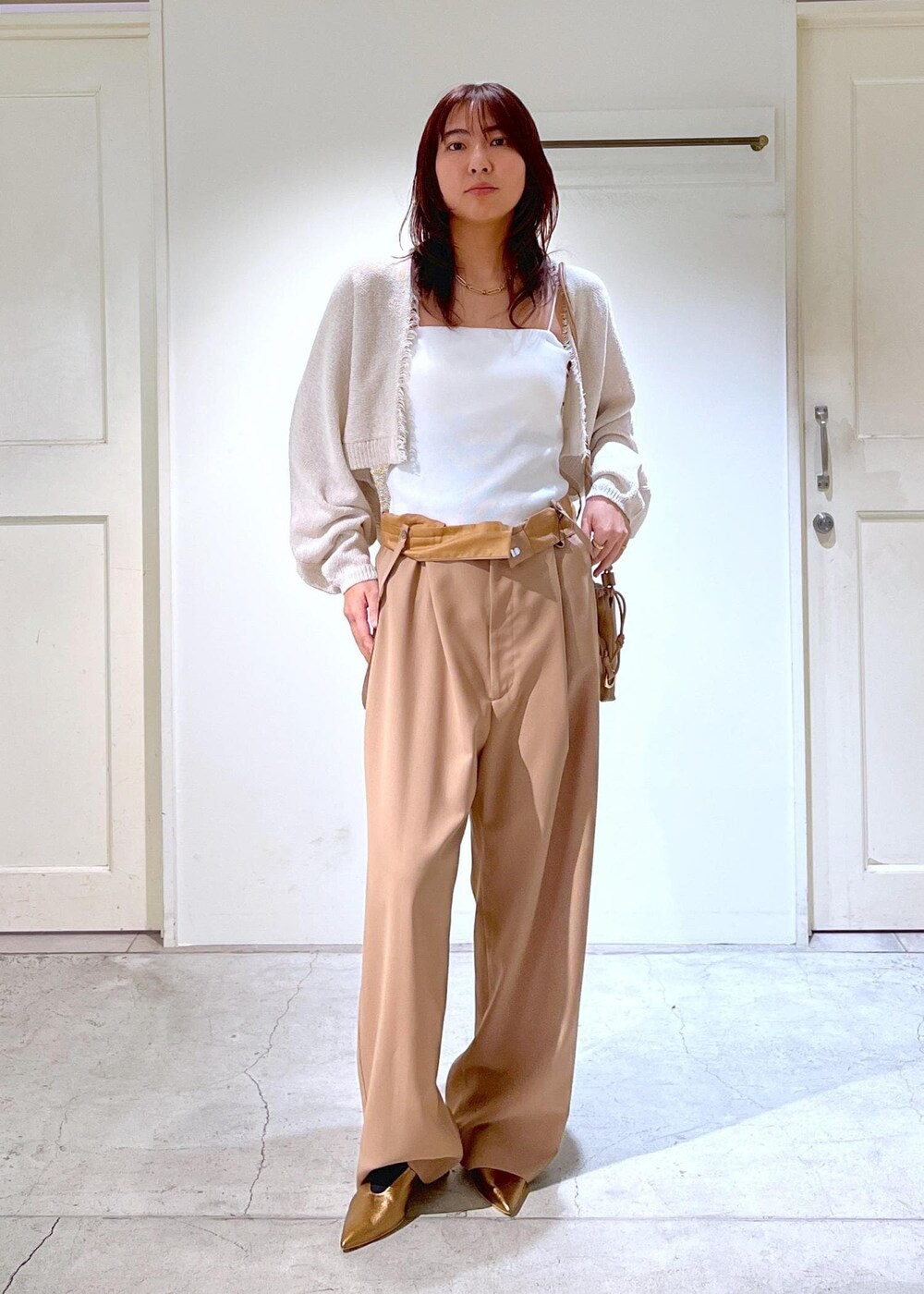 ホワイト系のチューブトップ、イエロー系のスラックス、ホワイト系のカーディガン/ボレロを着用したレディースの春コーディネートの2枚目の写真