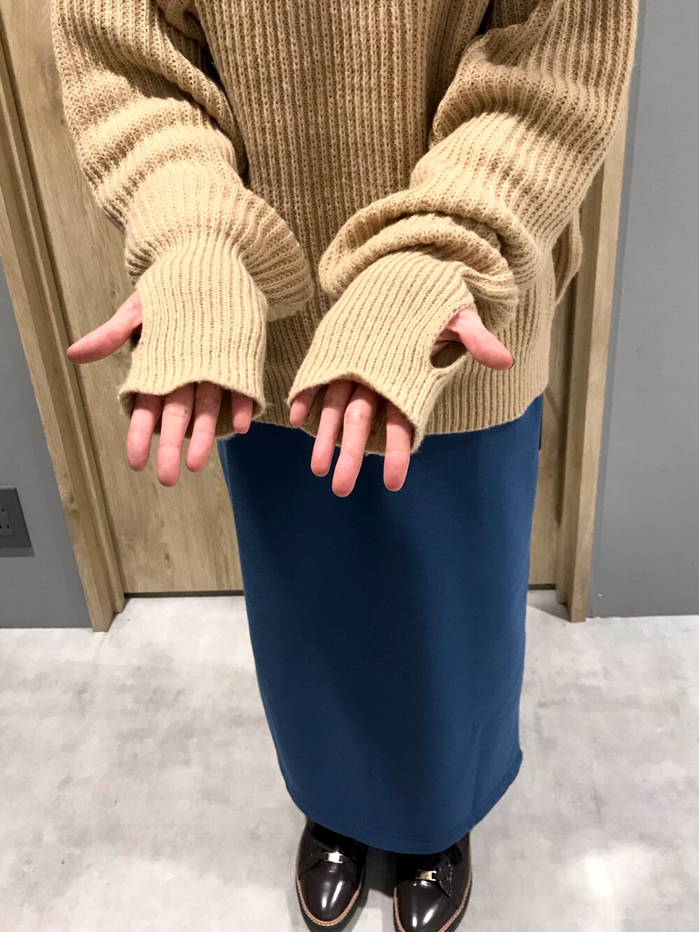 ベージュ系のニット/セーター、ブラウン系のスカート、ブラウン系のスニーカーを着用したレディースの秋コーディネートの2枚目の写真