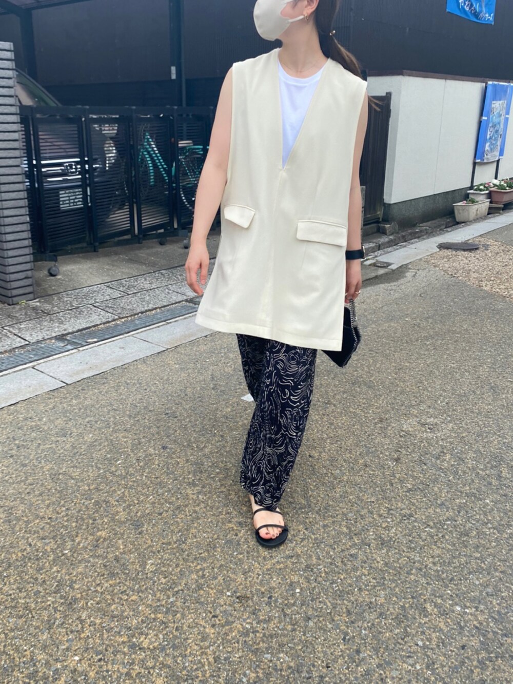 ブラック系のその他パンツ、ブラック系のサンダル、ホワイト系のベストを着用したレディースの夏コーディネートの2枚目の写真