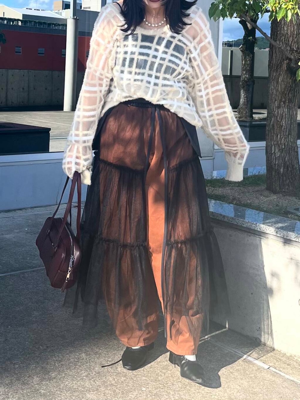 レッド系のボストンバッグ、グレー系のスカート、ベージュ系のニット/セーターを着用したレディースの夏コーディネートの3枚目の写真