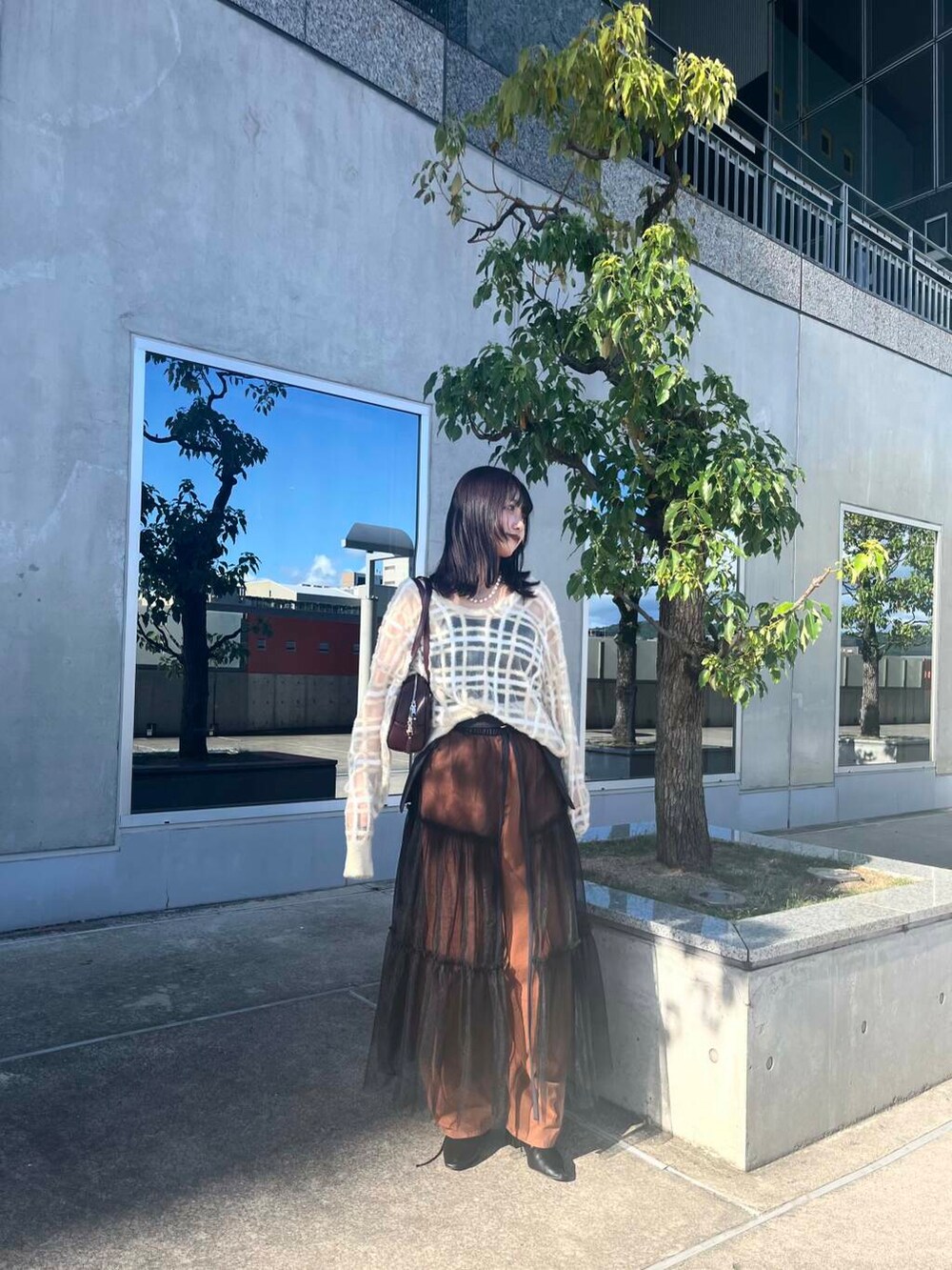 レッド系のボストンバッグ、グレー系のスカート、ベージュ系のニット/セーターを着用したレディースの夏コーディネートの5枚目の写真