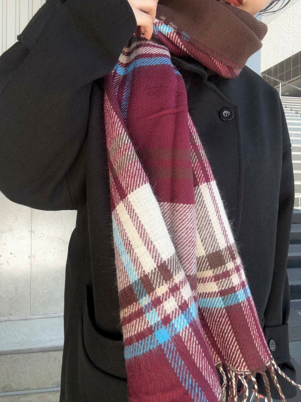 ブラック系のステンカラーコート、グレー系のワンピース、シルバー系のショルダーバッグを着用したレディースの冬コーディネートの3枚目の写真