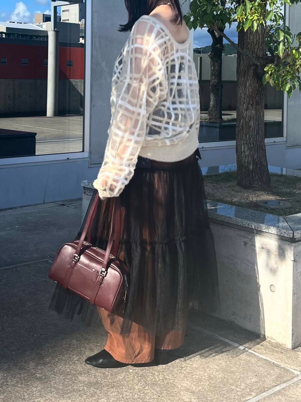 レッド系のボストンバッグ、グレー系のスカート、ベージュ系のニット/セーターを着用したレディースの夏コーディネートの4枚目の写真