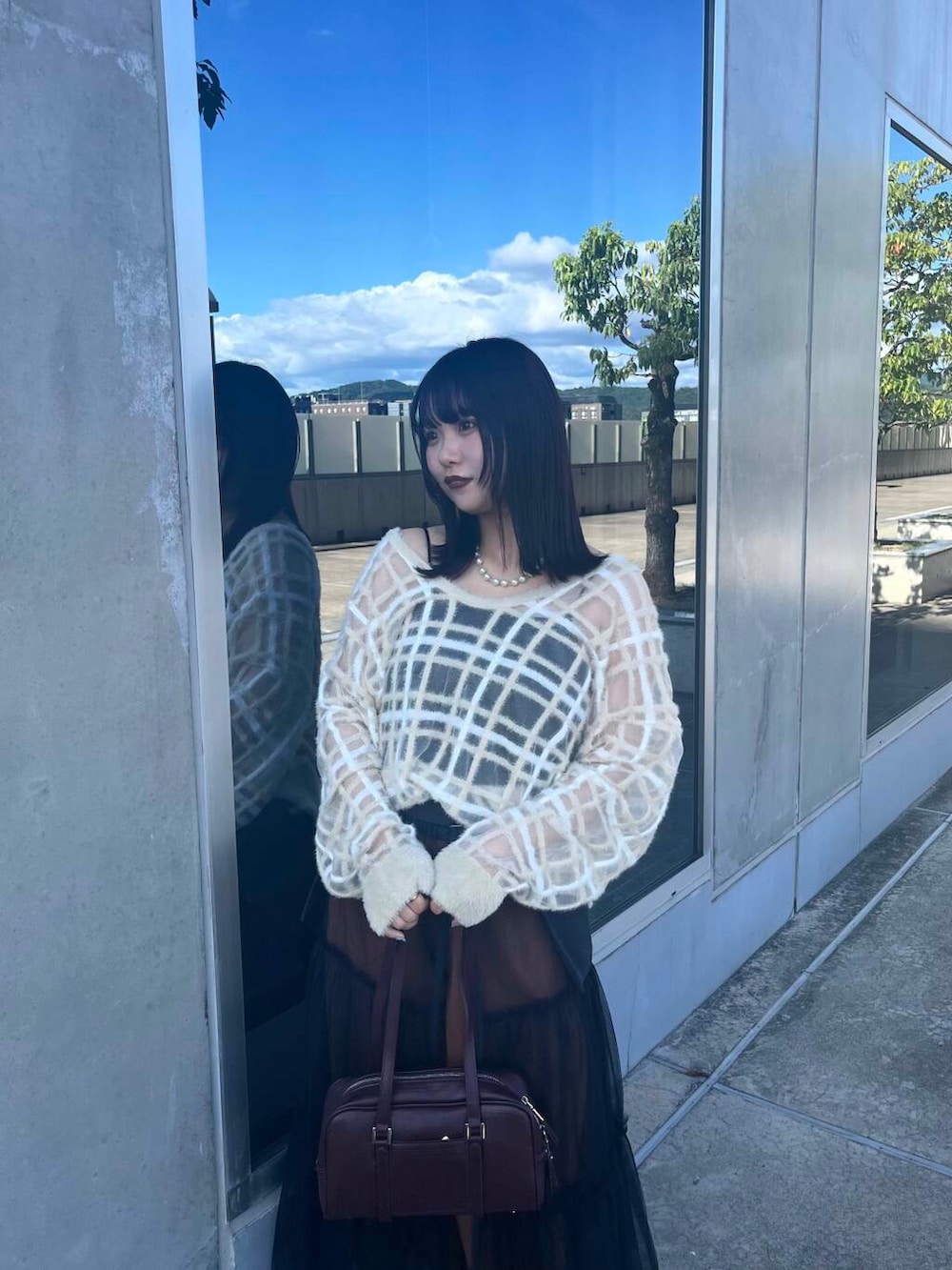 レッド系のボストンバッグ、グレー系のスカート、ベージュ系のニット/セーターを着用したレディースの夏コーディネートの2枚目の写真