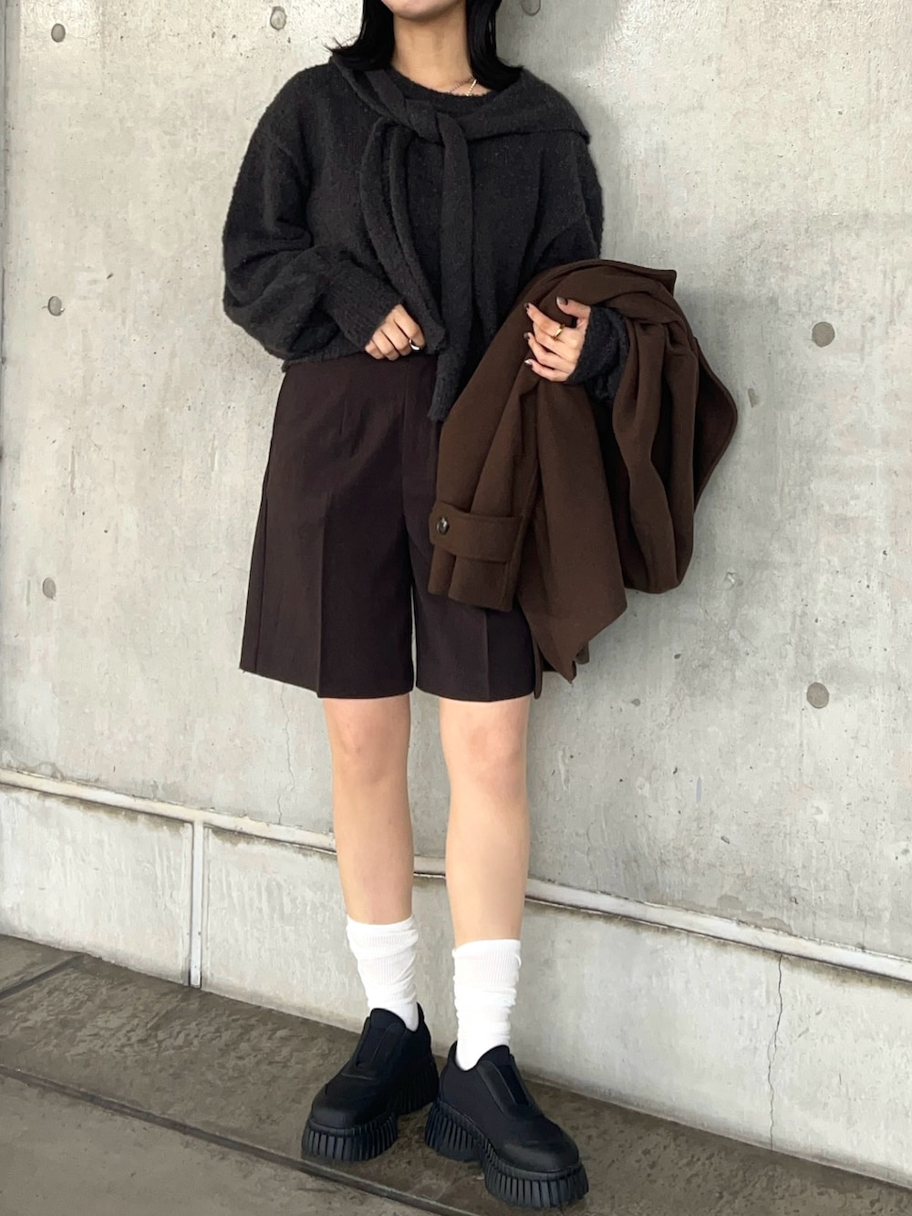 グレー系のニット/セーター、ブラウン系のその他パンツ、ブラック系のスニーカーを着用したレディースの秋コーディネートの5枚目の写真