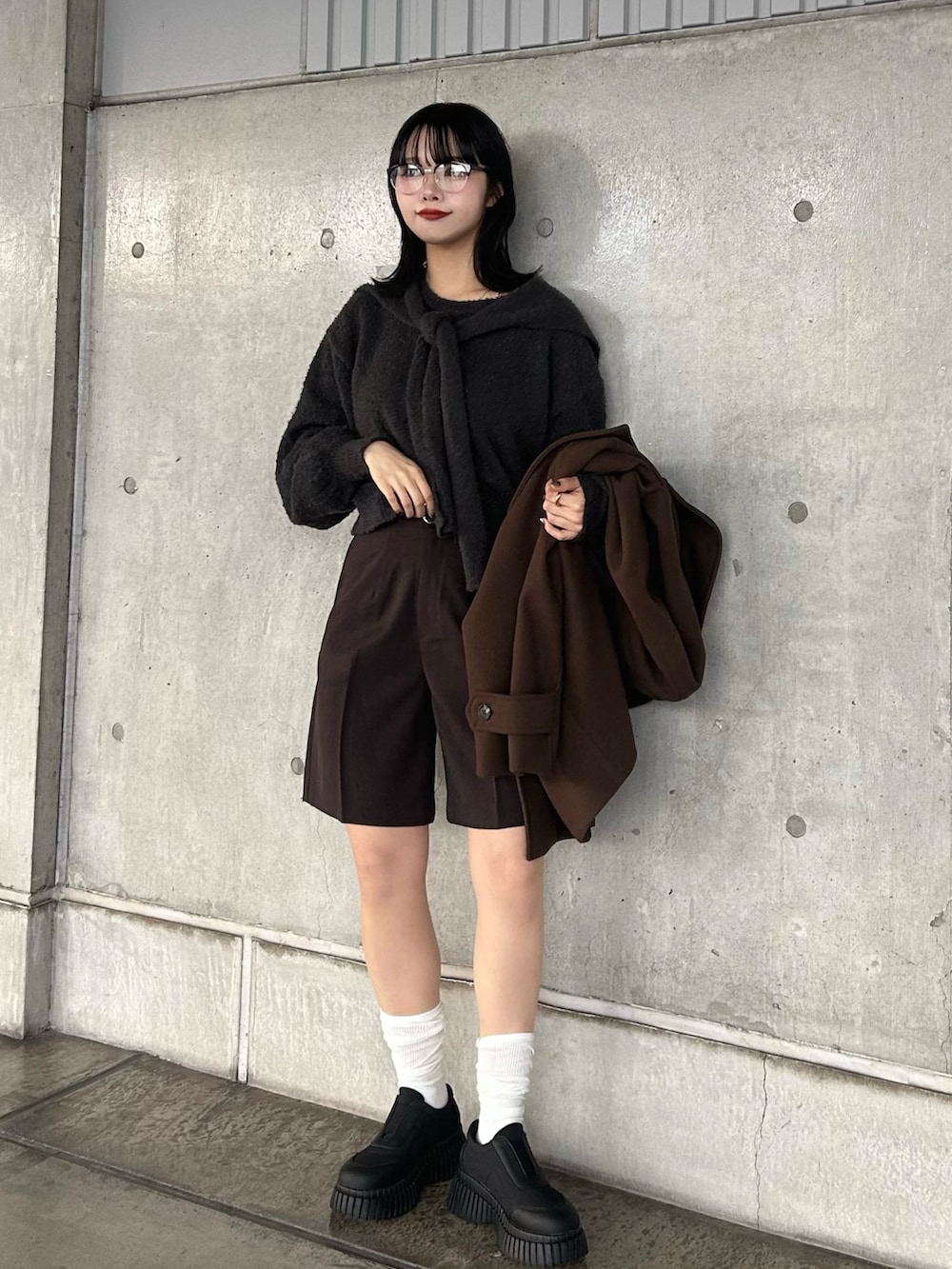 グレー系のニット/セーター、ブラウン系のその他パンツ、ブラック系のスニーカーを着用したレディースの秋コーディネートの3枚目の写真