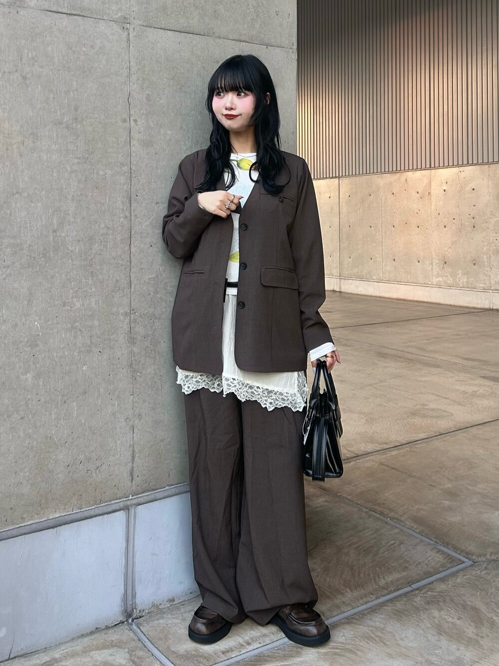 ブラウン系のノーカラージャケット、ブラウン系のその他パンツ、ホワイト系のキャミソールを着用したレディースの冬コーディネートの3枚目の写真