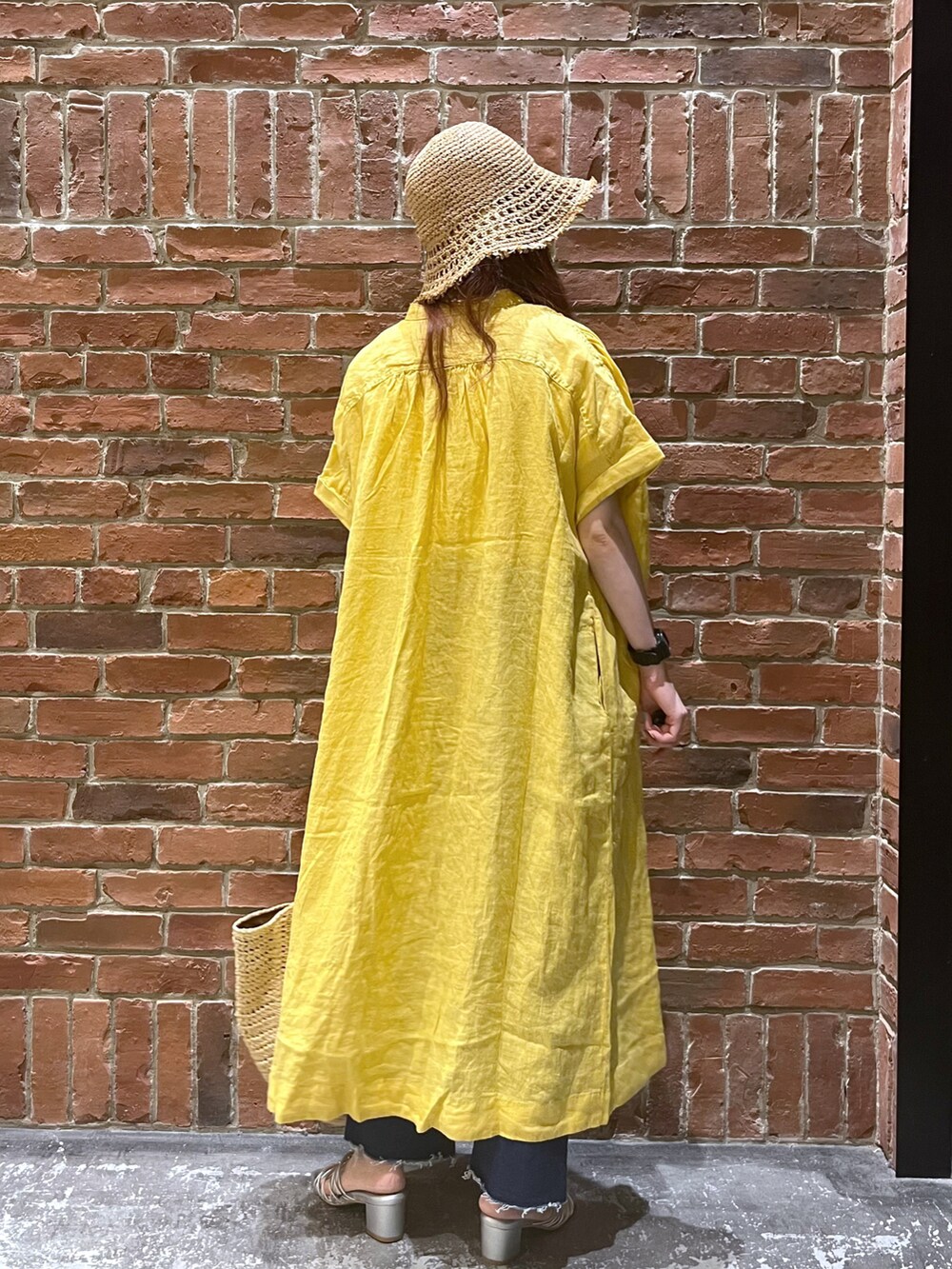 ブルー系のデニムパンツ、イエロー系のトートバッグ、グレー系のサンダルを着用したレディースの春コーディネートの3枚目の写真