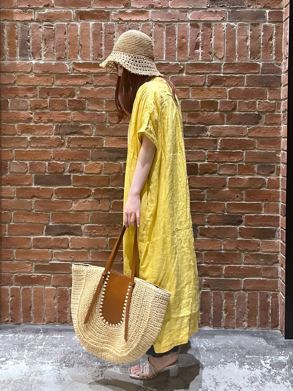 ブルー系のデニムパンツ、イエロー系のトートバッグ、グレー系のサンダルを着用したレディースの春コーディネートの2枚目の写真