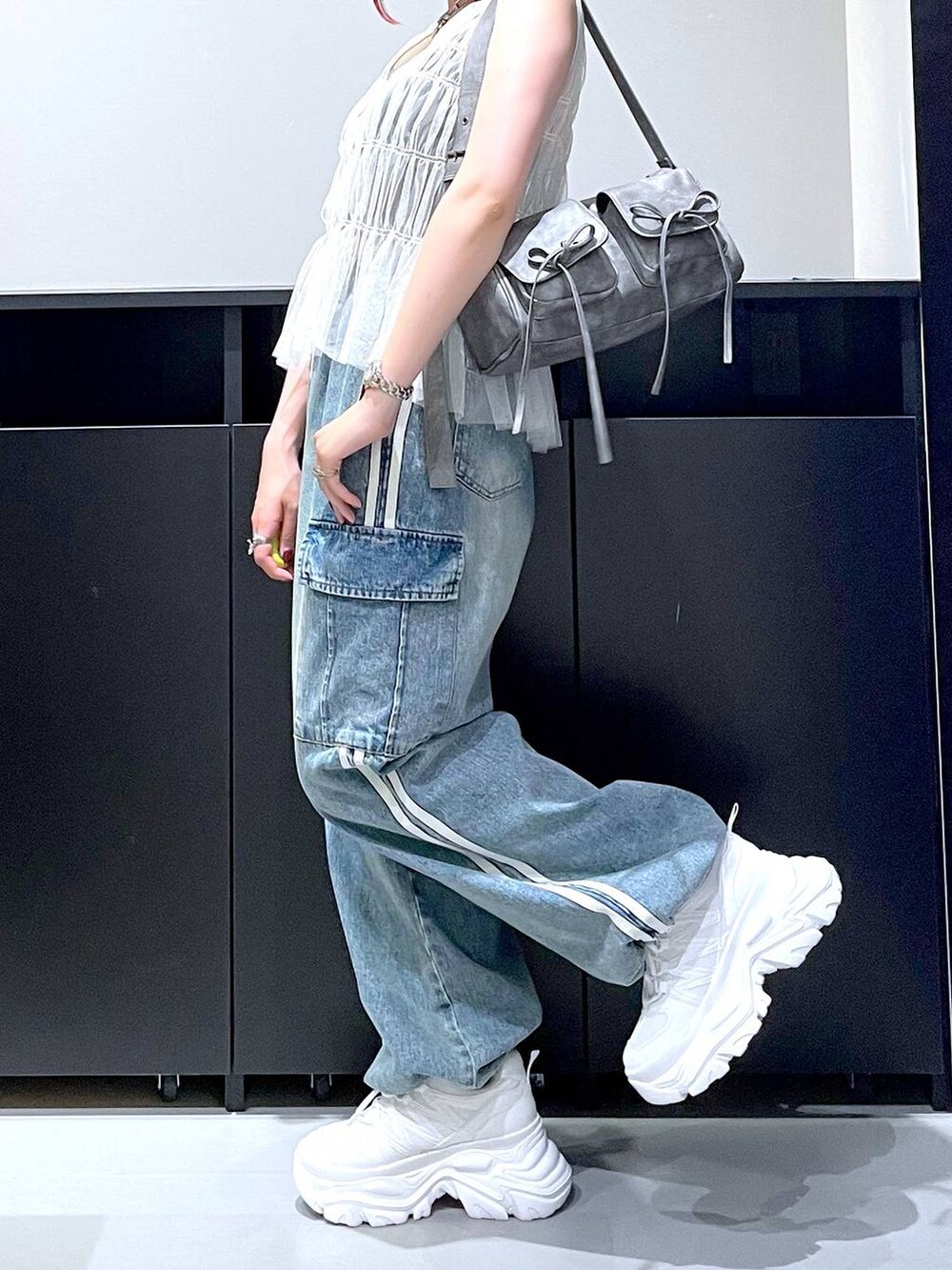 ホワイト系のスニーカー、ブルー系のデニムパンツ、グレー系のショルダーバッグを着用したレディースの夏コーディネートの4枚目の写真