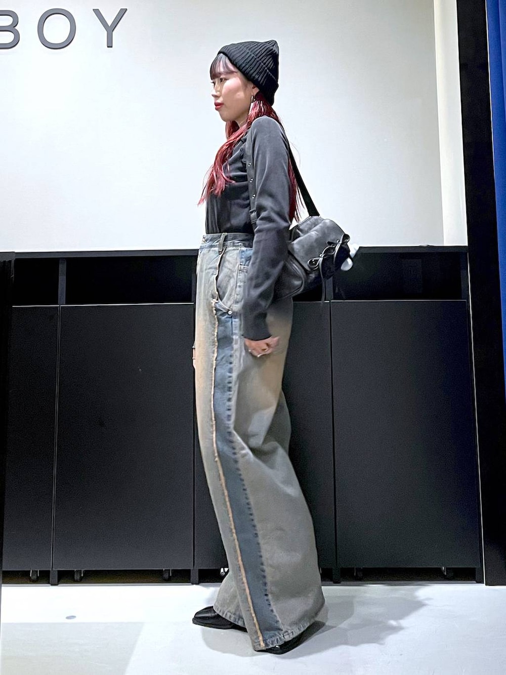 ブラック系のショルダーバッグ、ブルー系のデニムパンツ、ブラック系のブーツを着用したレディースの秋コーディネートの4枚目の写真